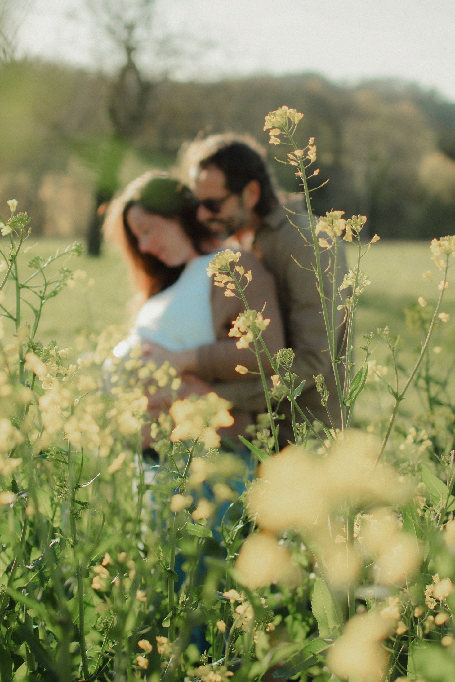 Couple attendant un enfant dans un champ de colza