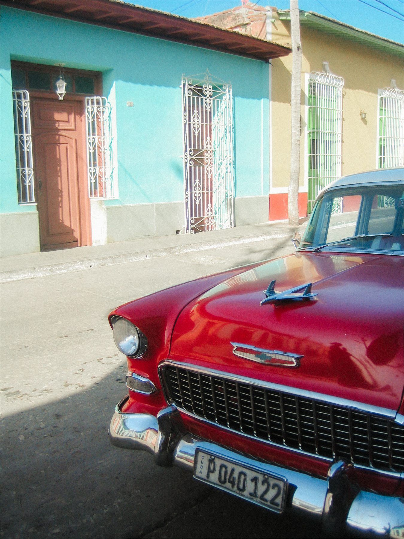 Voiture américaine rouge devant des façades colorées à Cuba