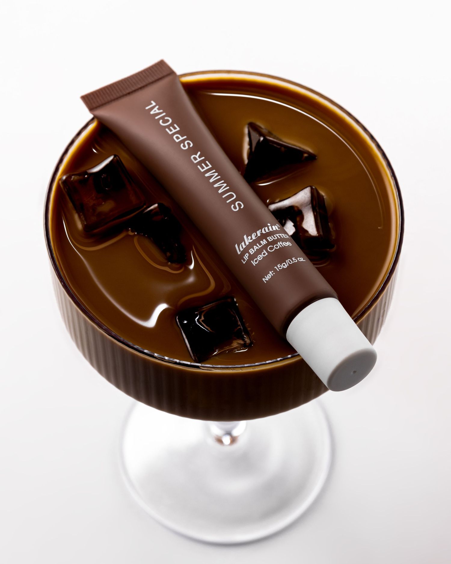 Lakerain Summer Special Iced Coffee Lip Balm Butter tube resting in a glass of iced coffee drink.