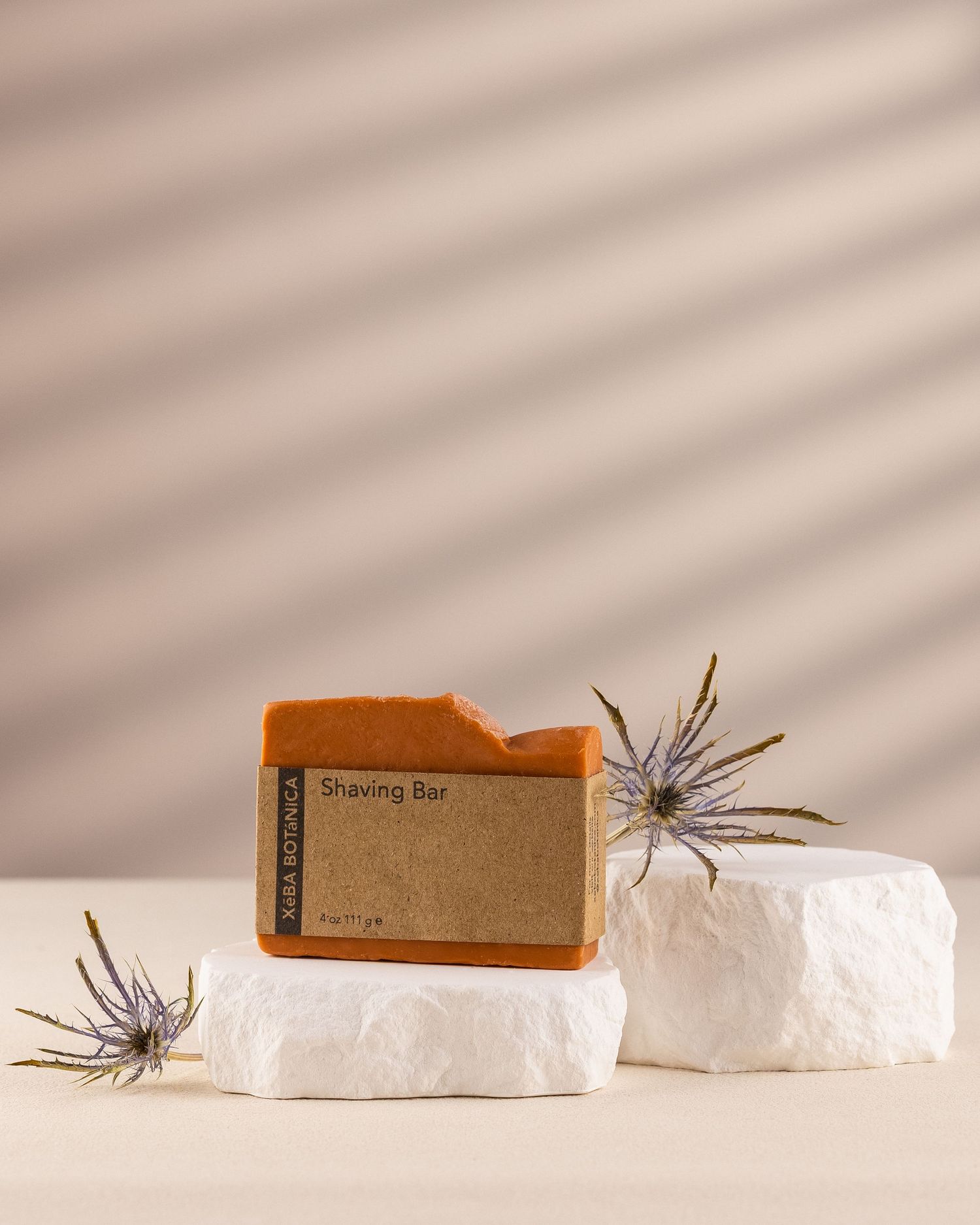 Xeba Botanica Shaving Bar soap on white stone pedestals with dried thistle flowers as decoration.