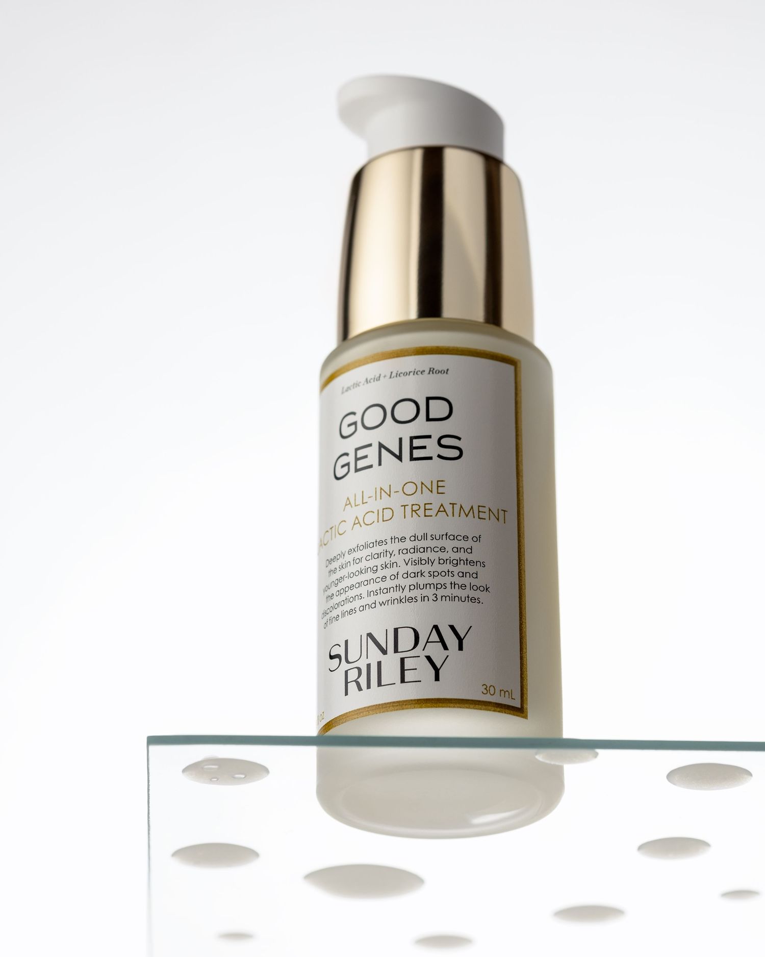 Sunday Riley Good Genes All-In-One Lactic Acid Treatment 30ml bottle with gold pump dispenser on glass.