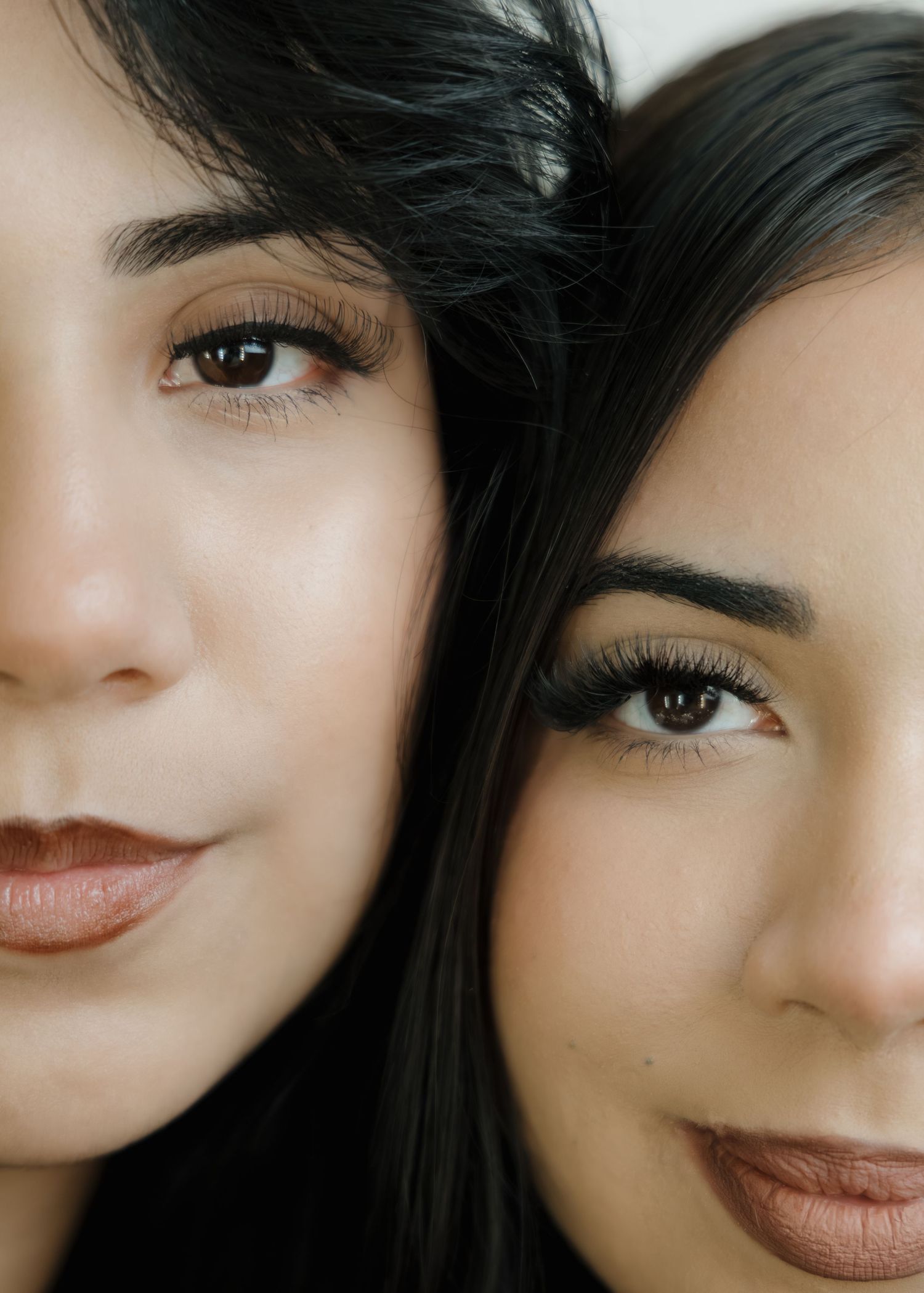 Close-up portrait of two dark-haired women with brown eyes and mauve lips side by side.