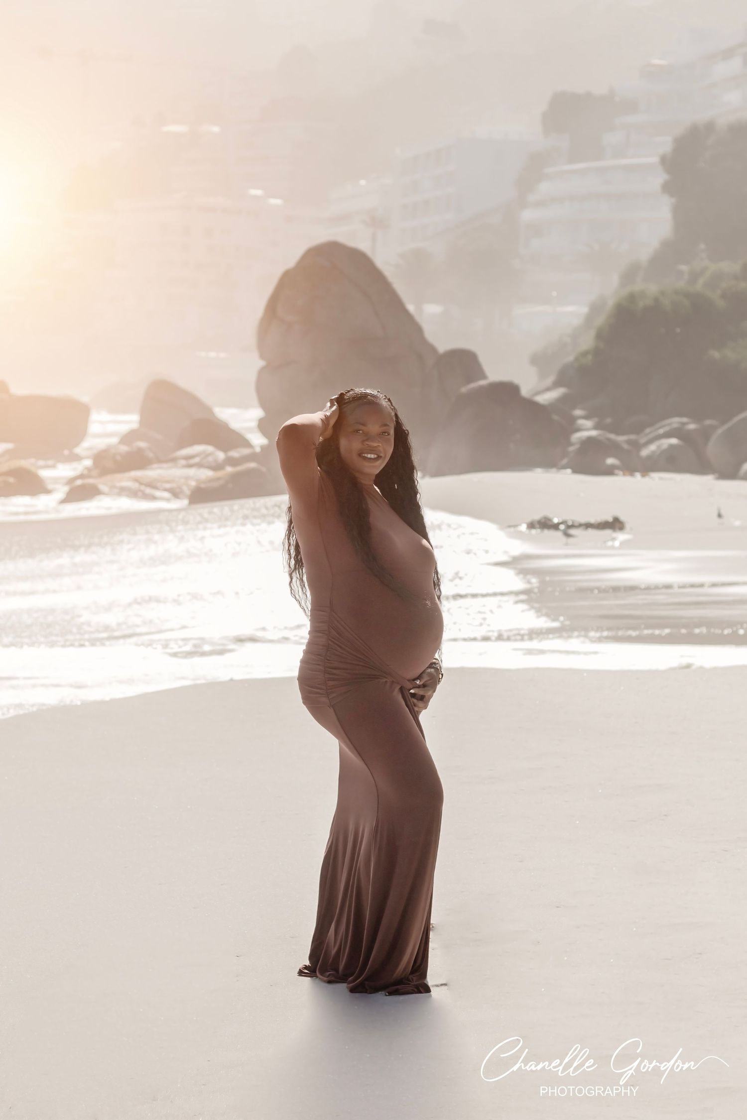 Maternity lifestyle portrait of a mother at sunset against the Twelve Apostles mountain backdrop