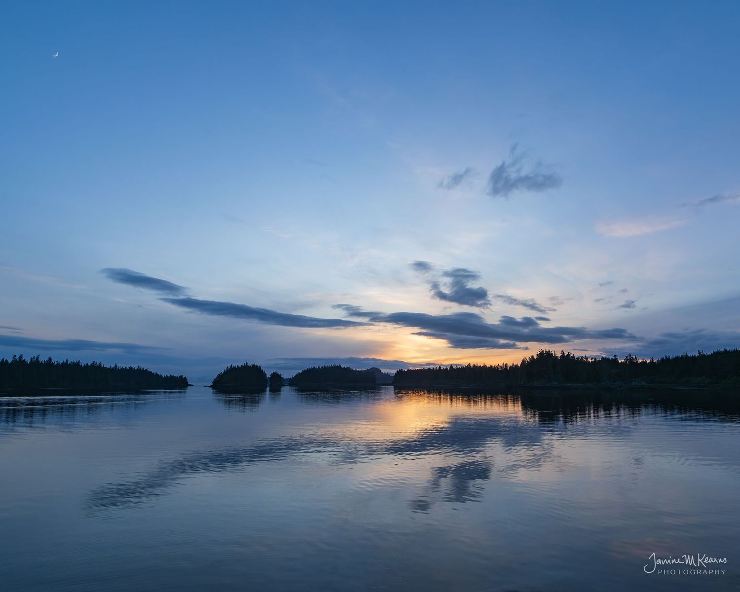 Sunset over Halleck Harbor in Southeastern Alaska. Tall evergreen trees on the shores. Serenity.