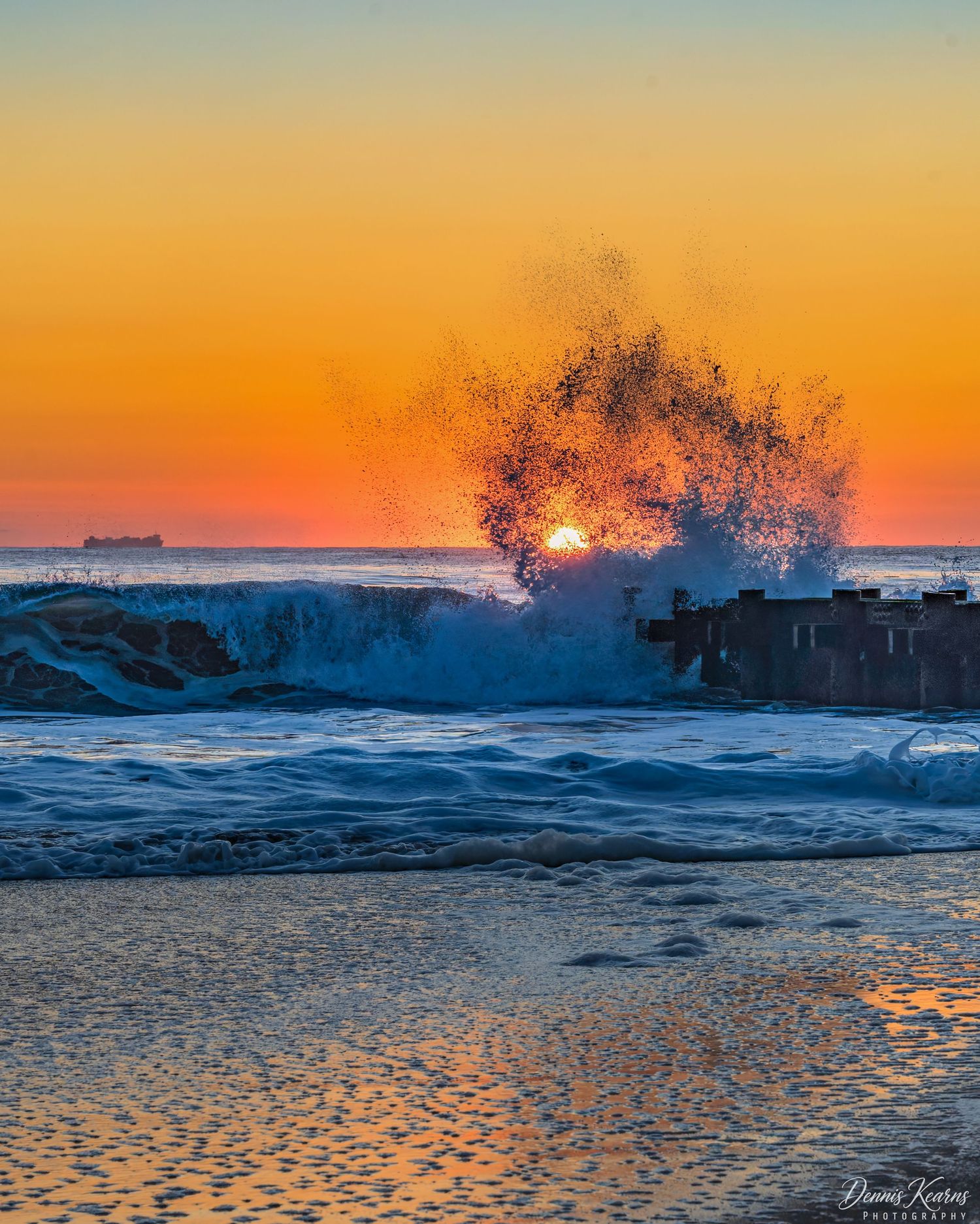 Sun rising behind a wave crashing into a Jetty at Rehoboth Beach