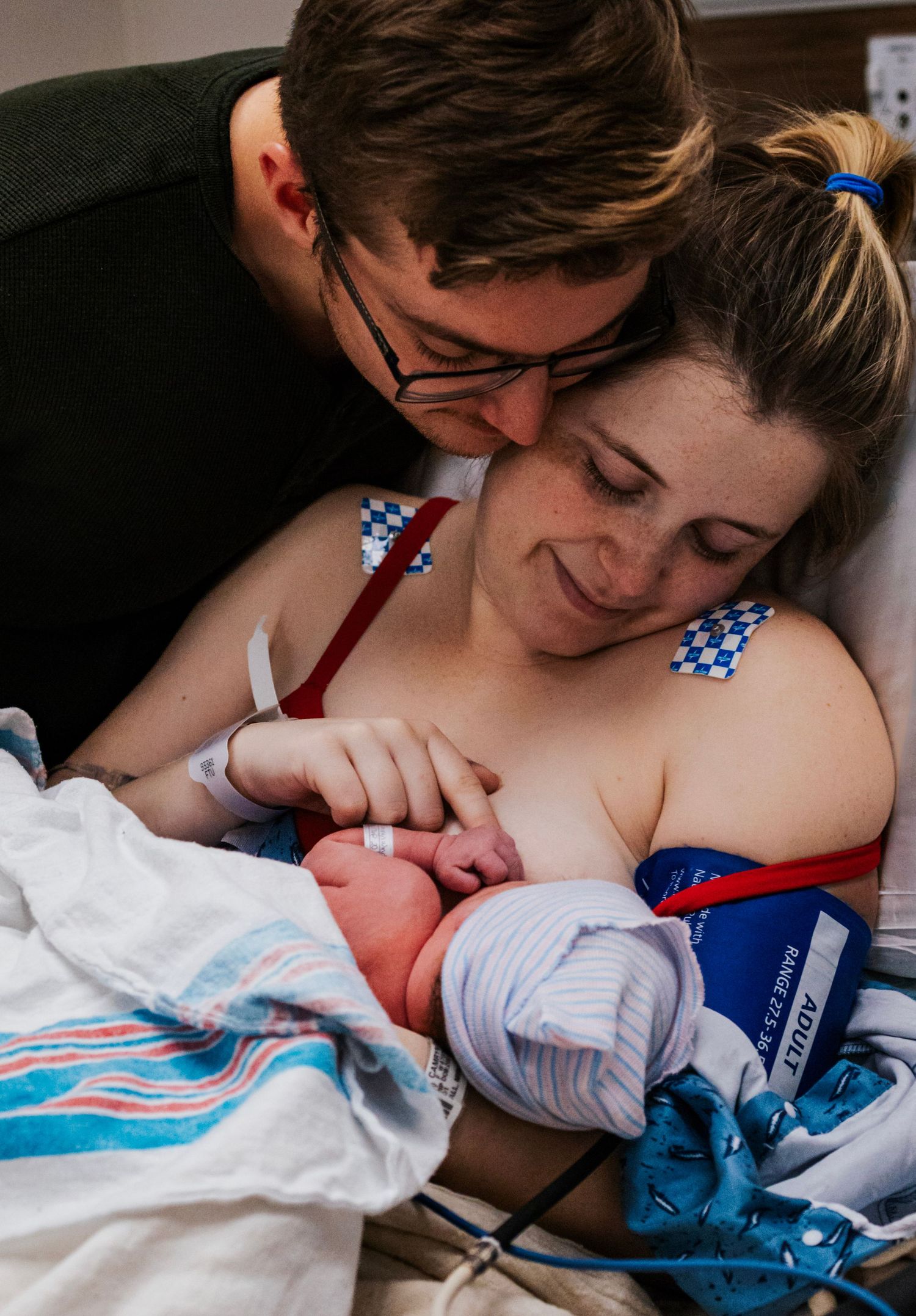 Loving couple smiling and bonding with their newborn baby in hospital room after delivery.