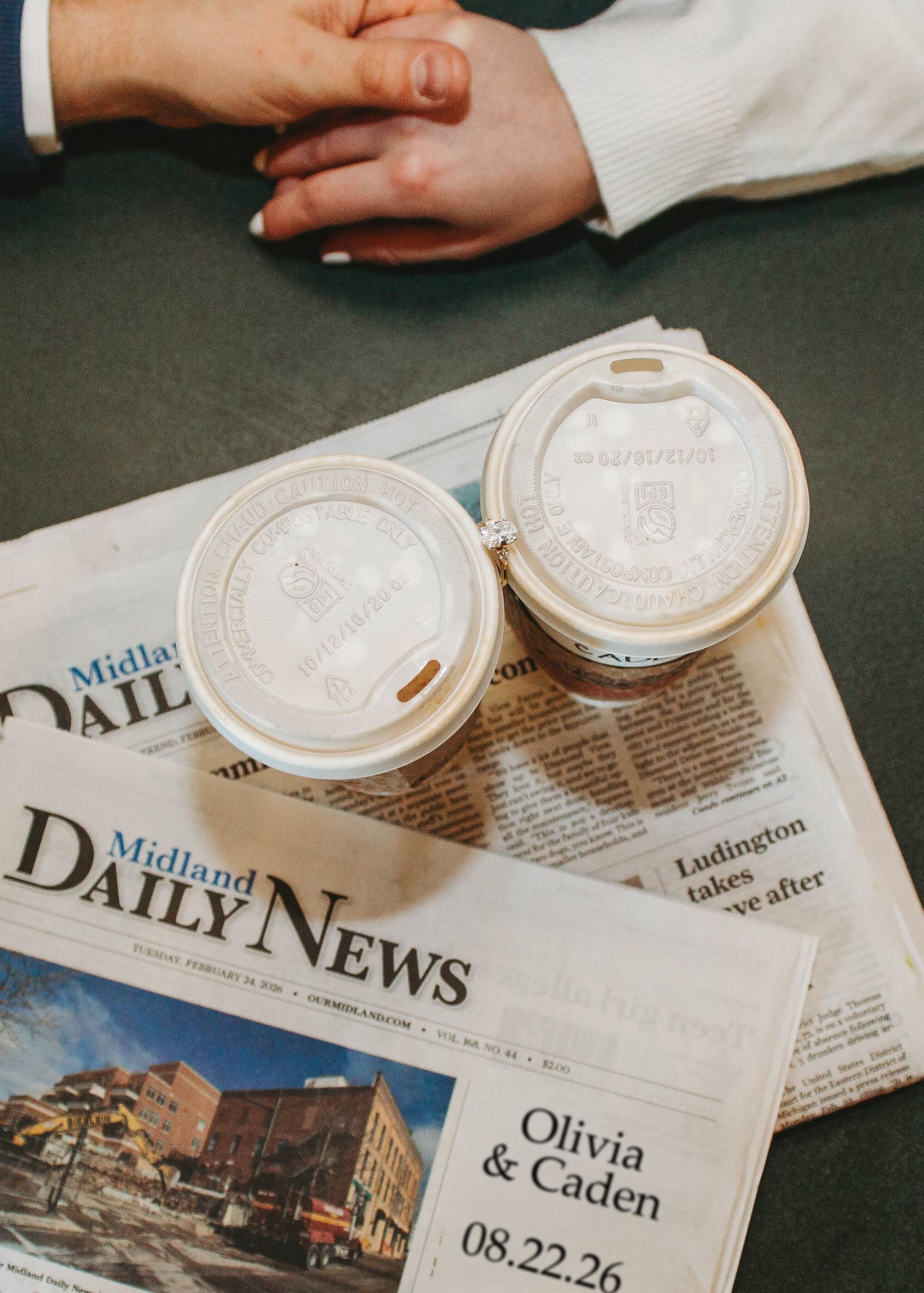 Two coffee cups on a Midland Daily News engagement announcement dated 08.22.26.