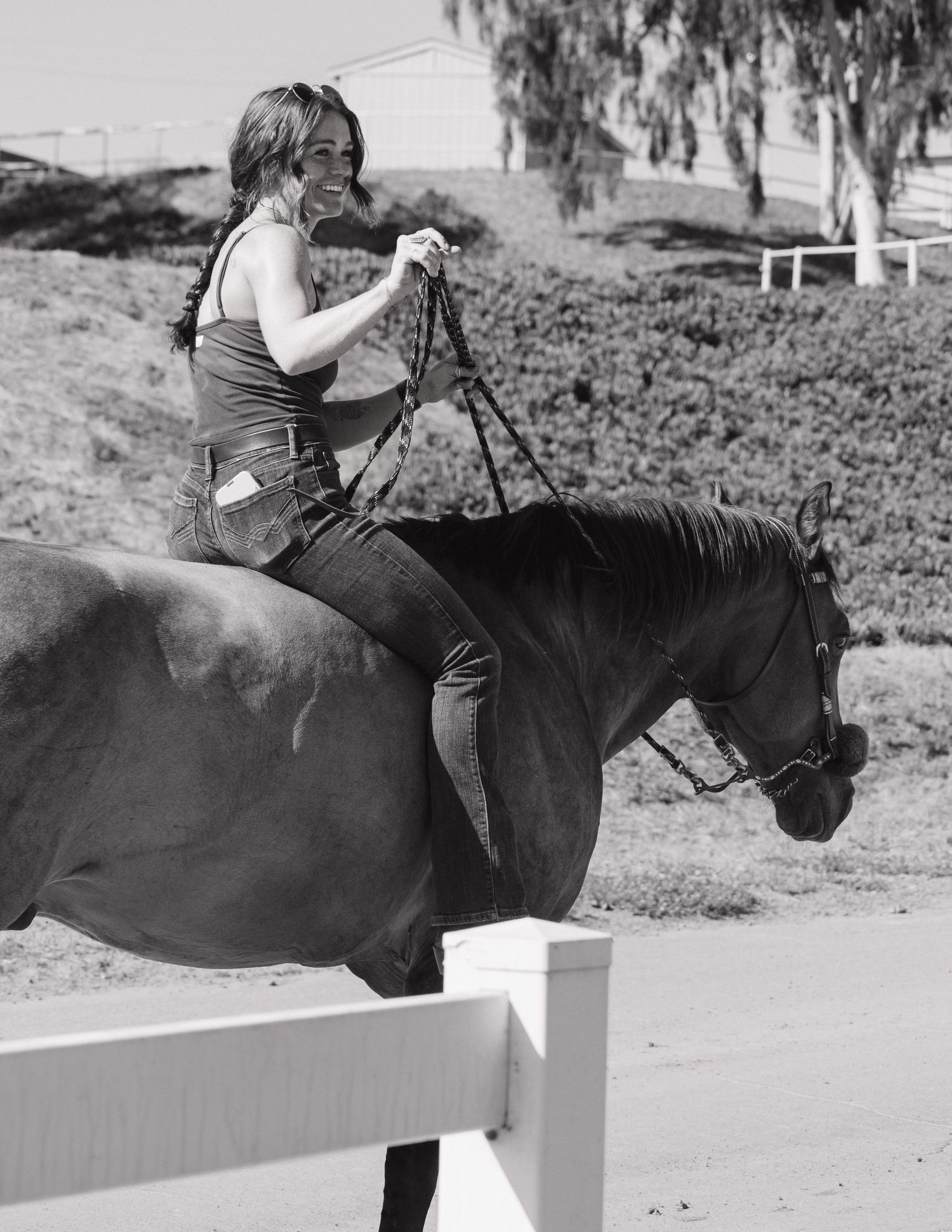 Woman riding dark horse bareback in black and white equestrian photo.