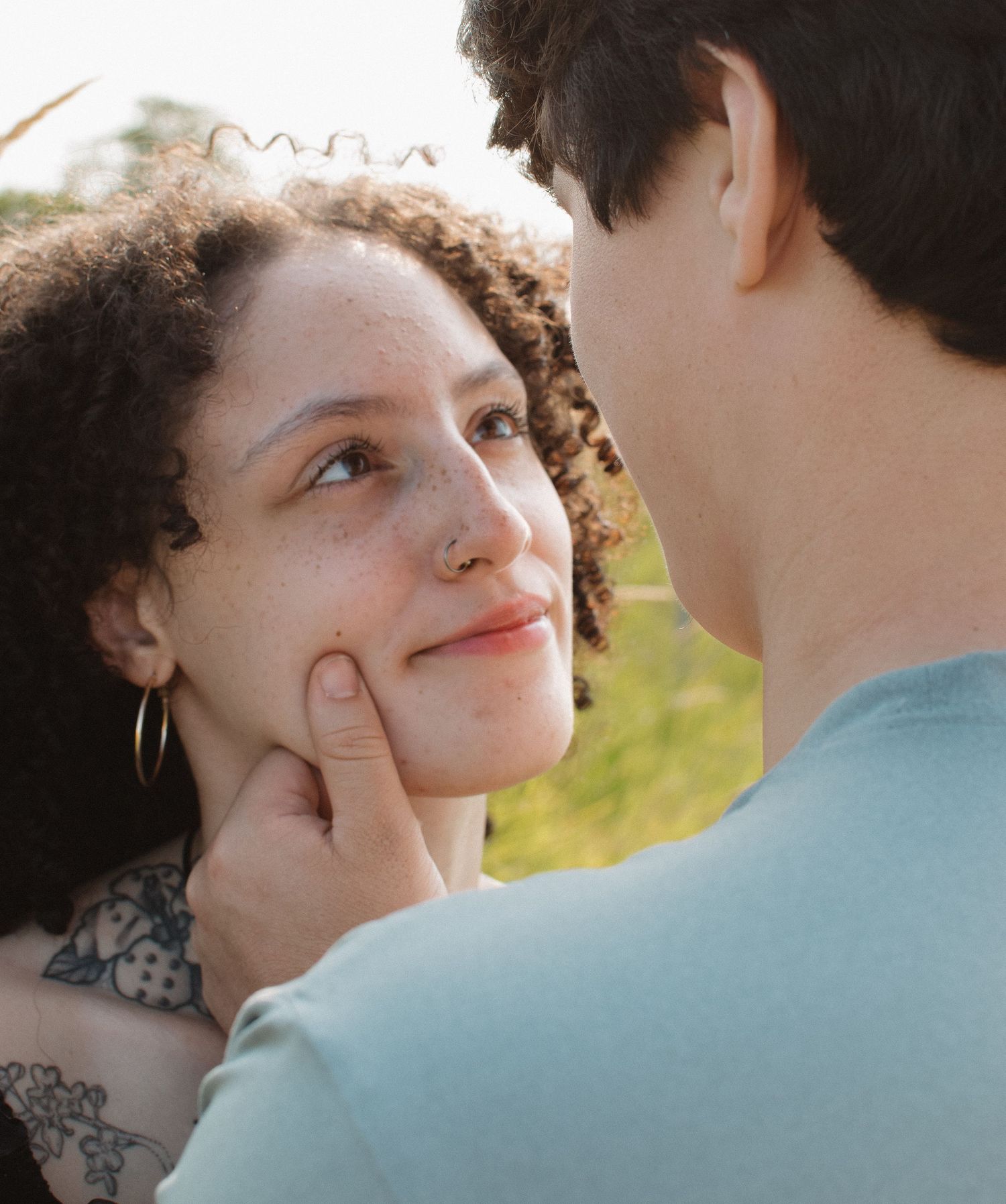 Young couple sharing a tender moment outdoors, man touching womans cheek affectionately.