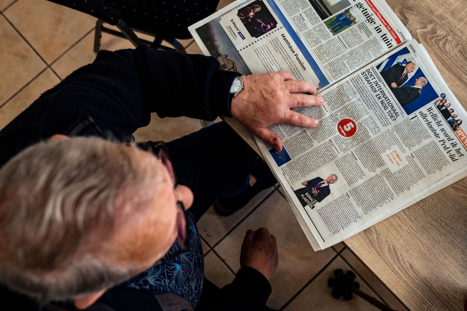 Overhead view of newspapers spread across a tiled surface.
