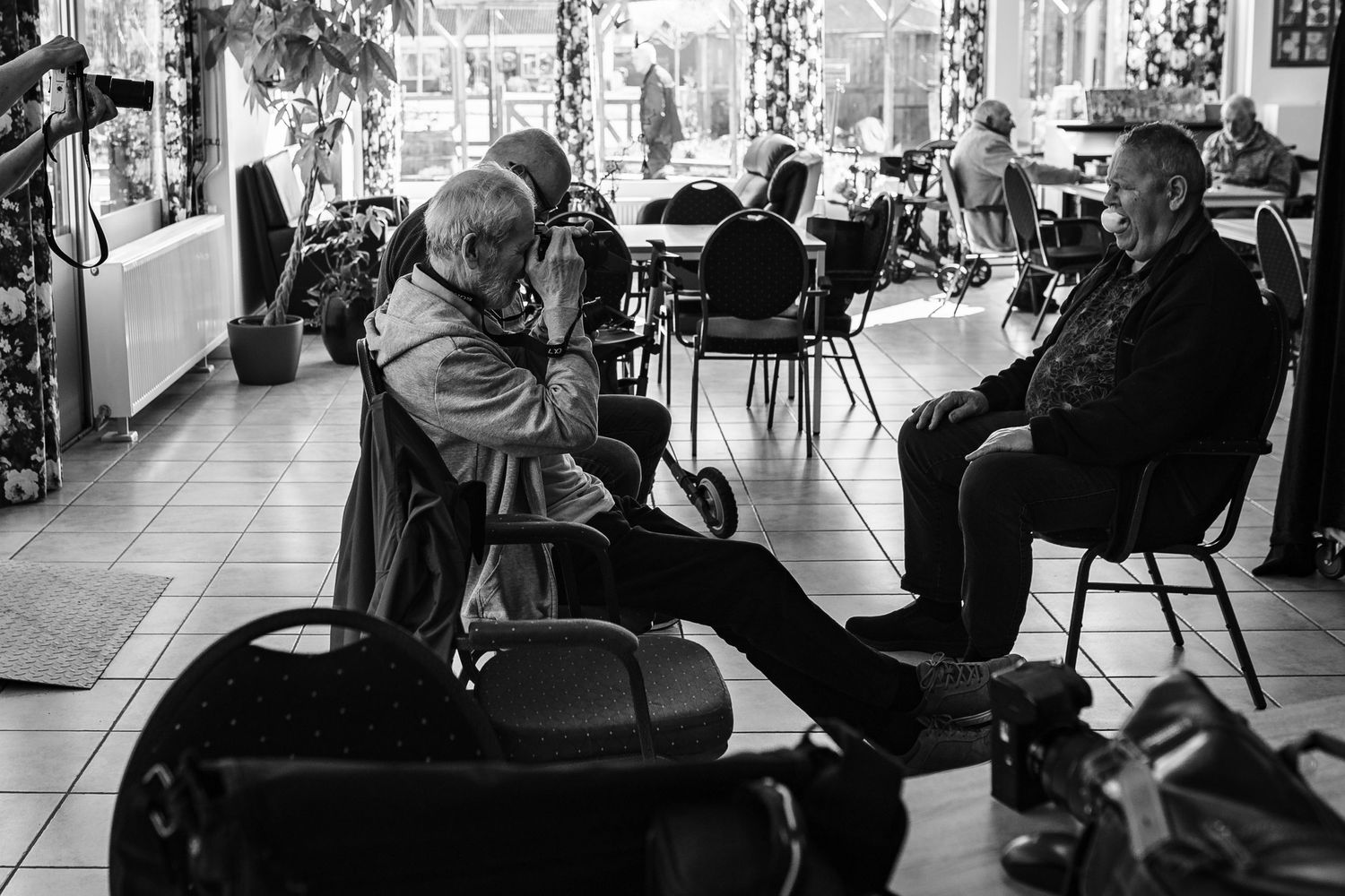 People sitting and conversing in a casual indoor setting with chairs and tables.