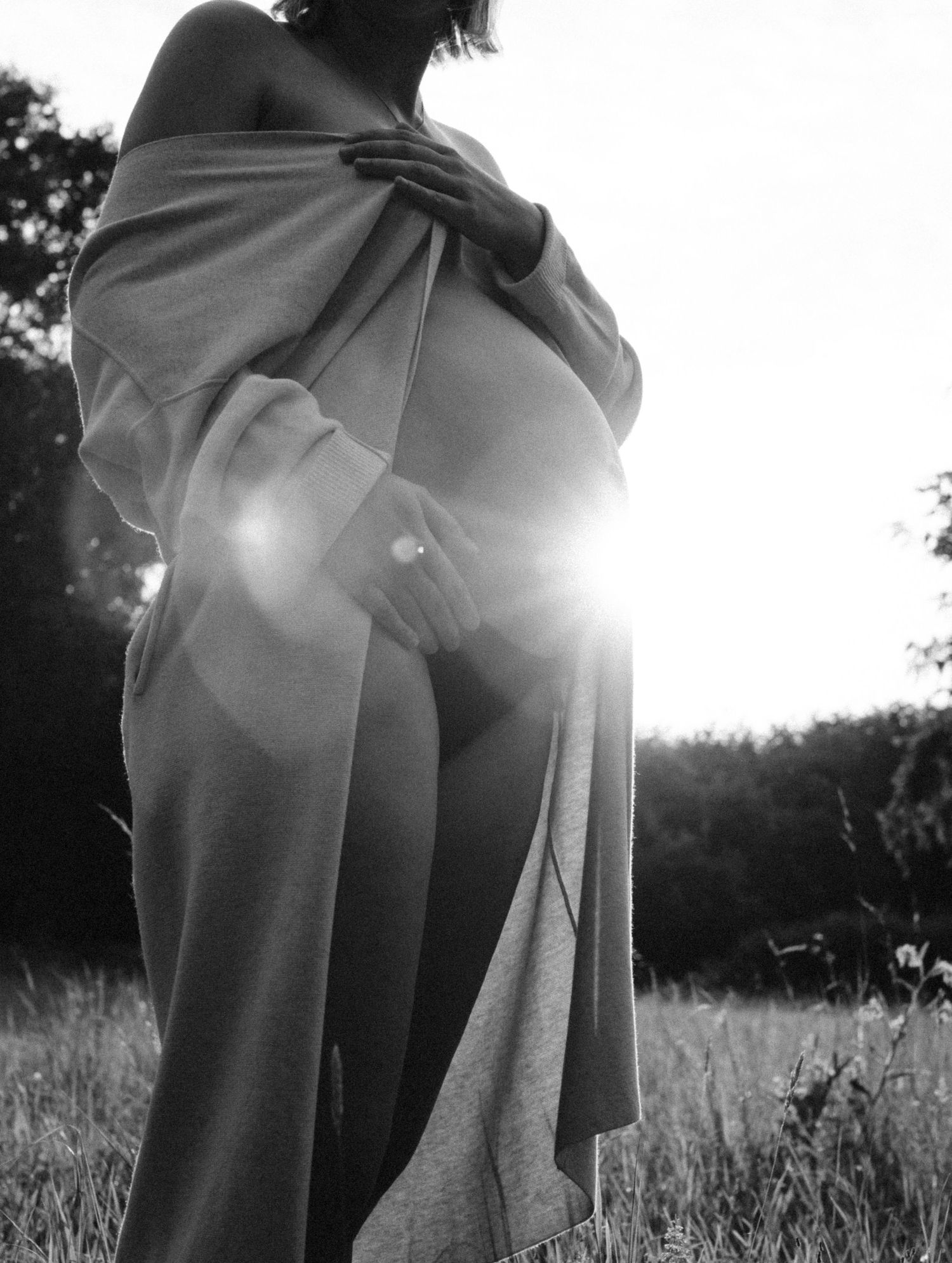 Dramatic black and white backlit maternity photo of woman wrapped in fabric in golden sunlight. By Soft Sacred Studios.