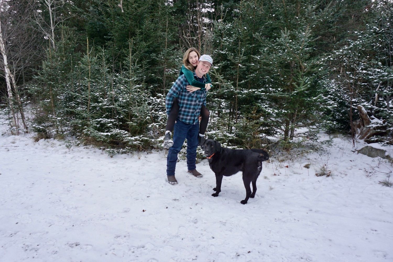 couple and dog playing in the woods