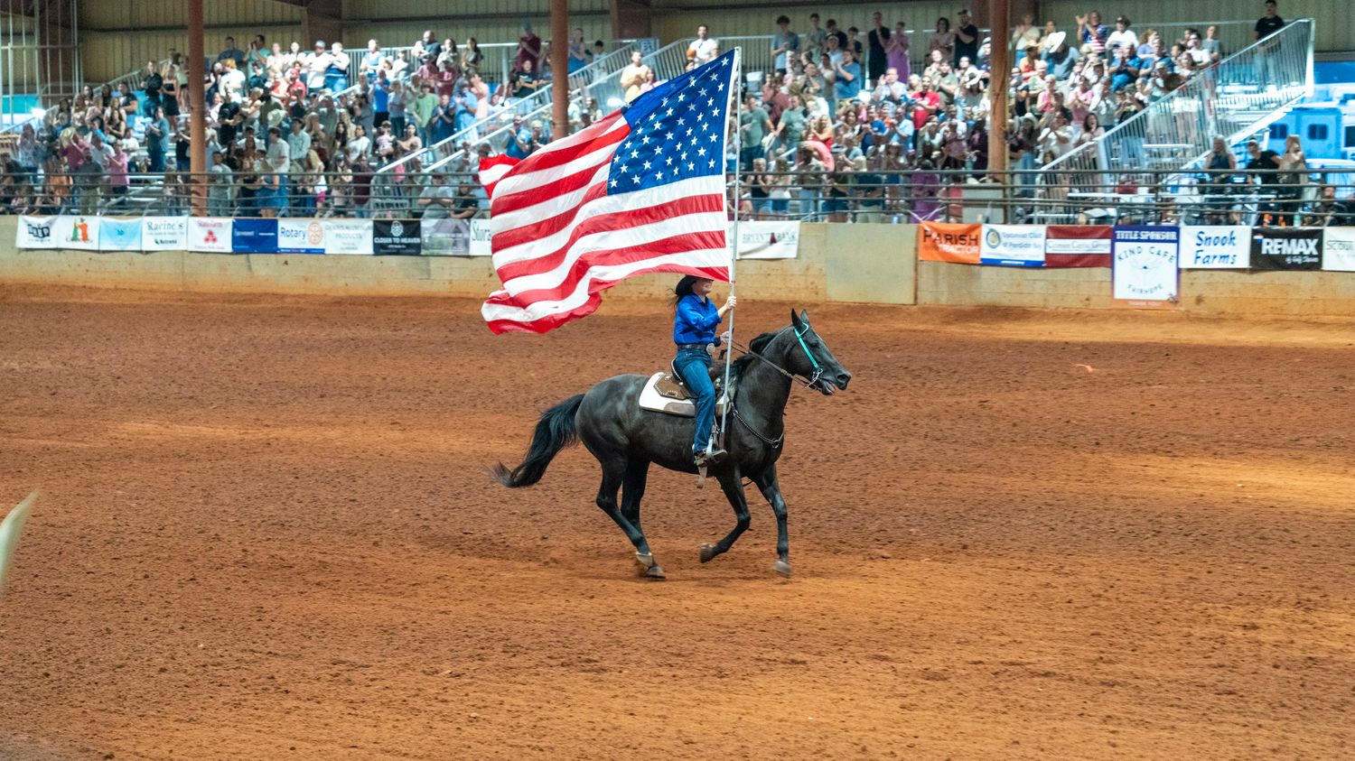 American flag being carried by woman on horseback