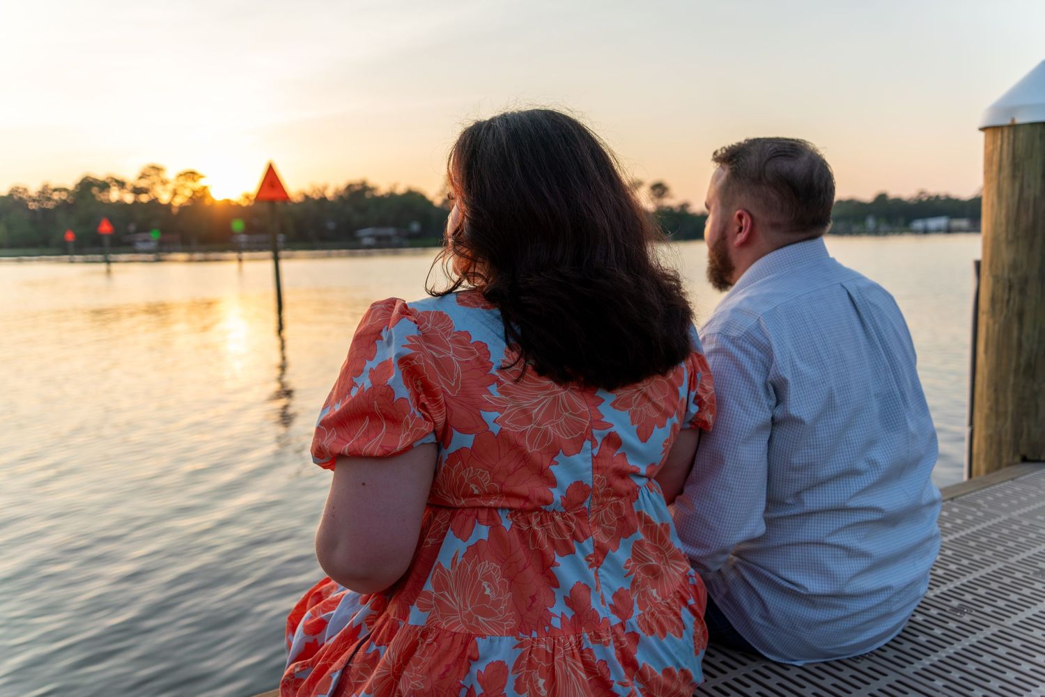 couple sitting on dock in front of sunset