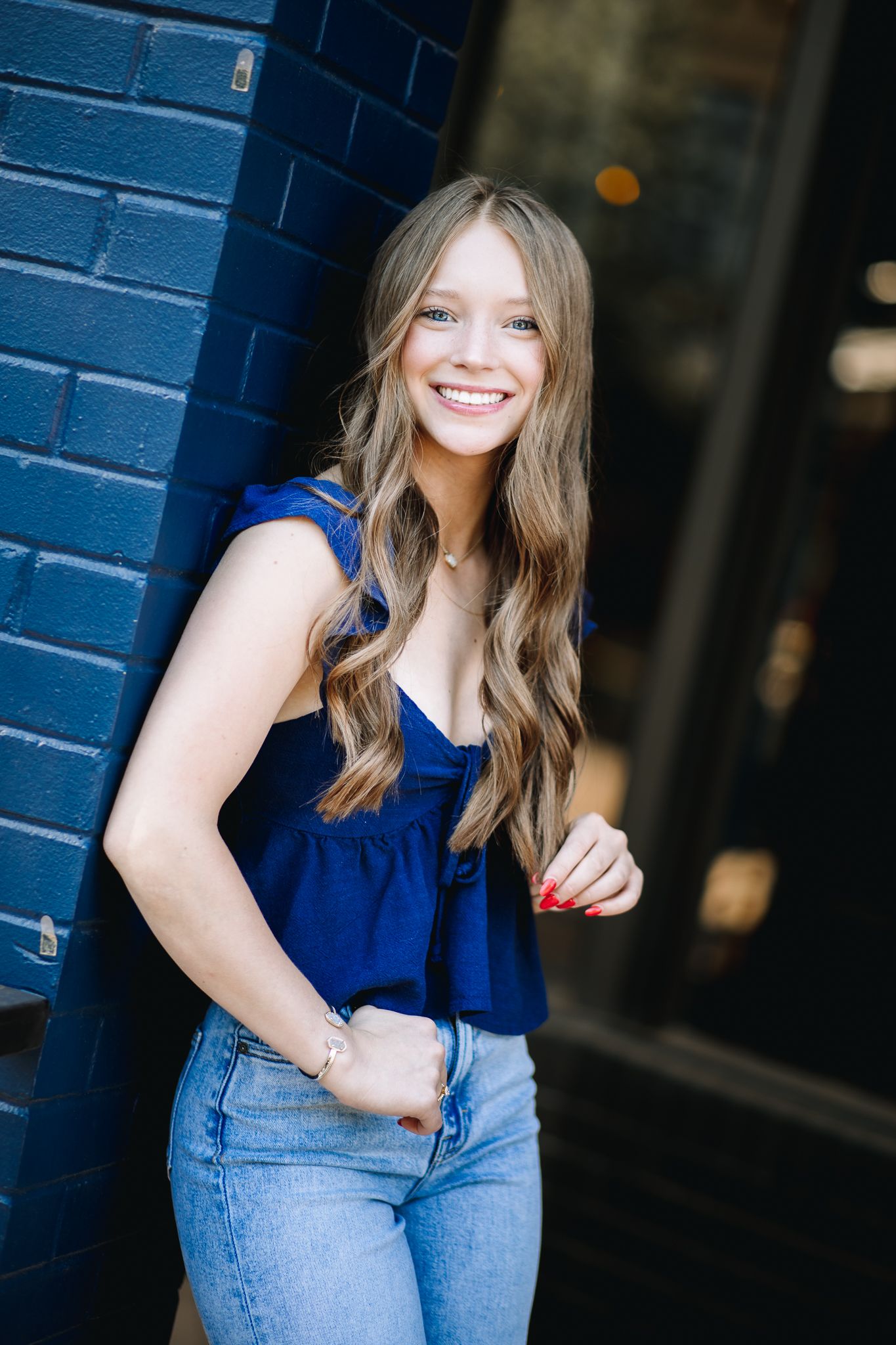 class of 2026 high school senior in Windsor Colorado posing for her senior pictures in a blue shirt softly smiling at the photographer