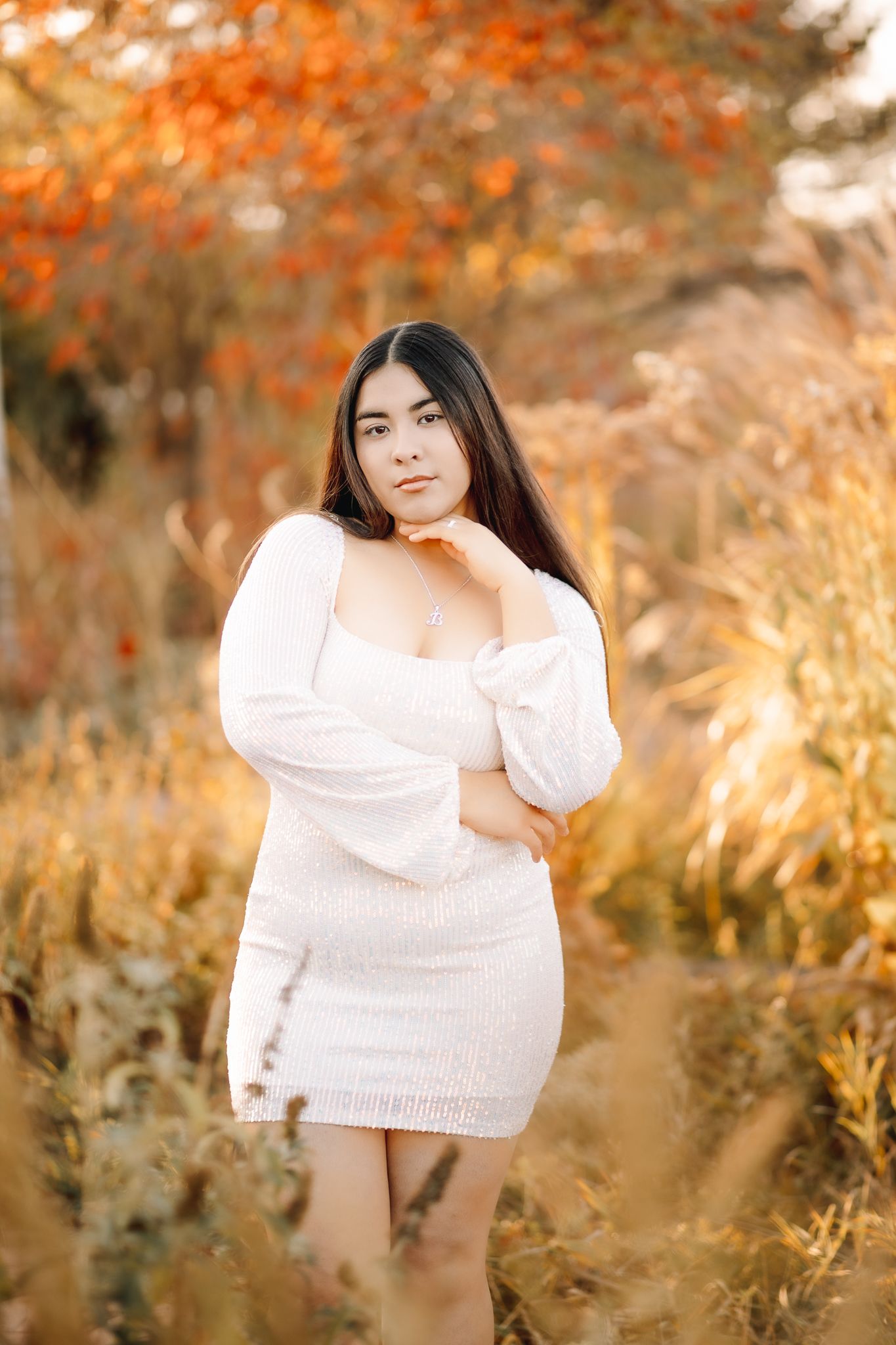 class of 2026 high school senior in Windsor Colorado posing for her senior pictures in white dress softly smiling at the photographer