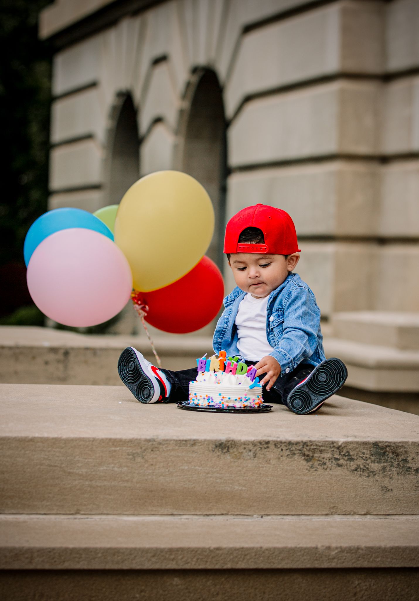 boy posing for his 1st birthday cake smash photoshoot during fall time