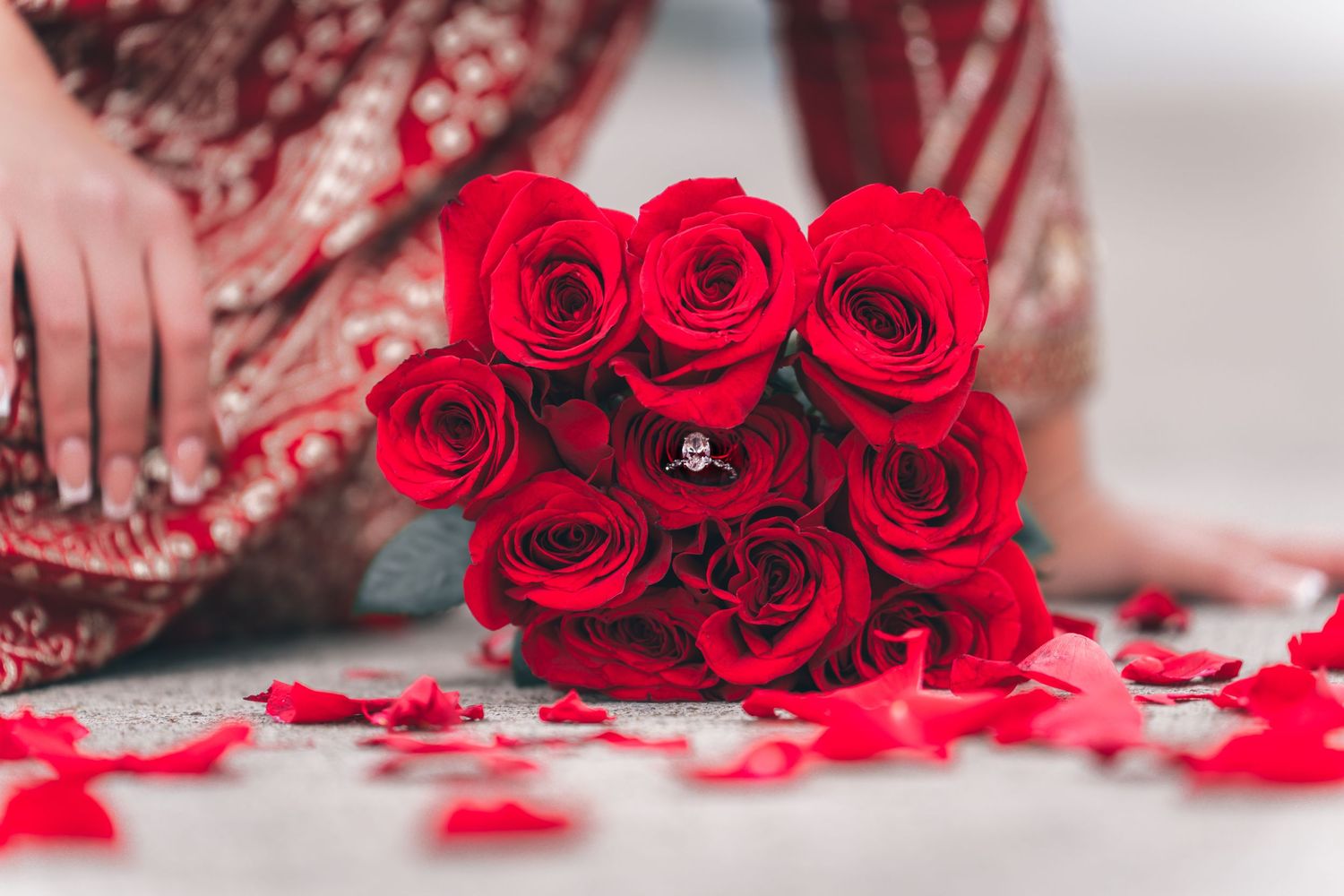 Romantic red roses bouquet embeded with engagement ring in middle with scattered petals for wedding photography captured by Ionframe Studio