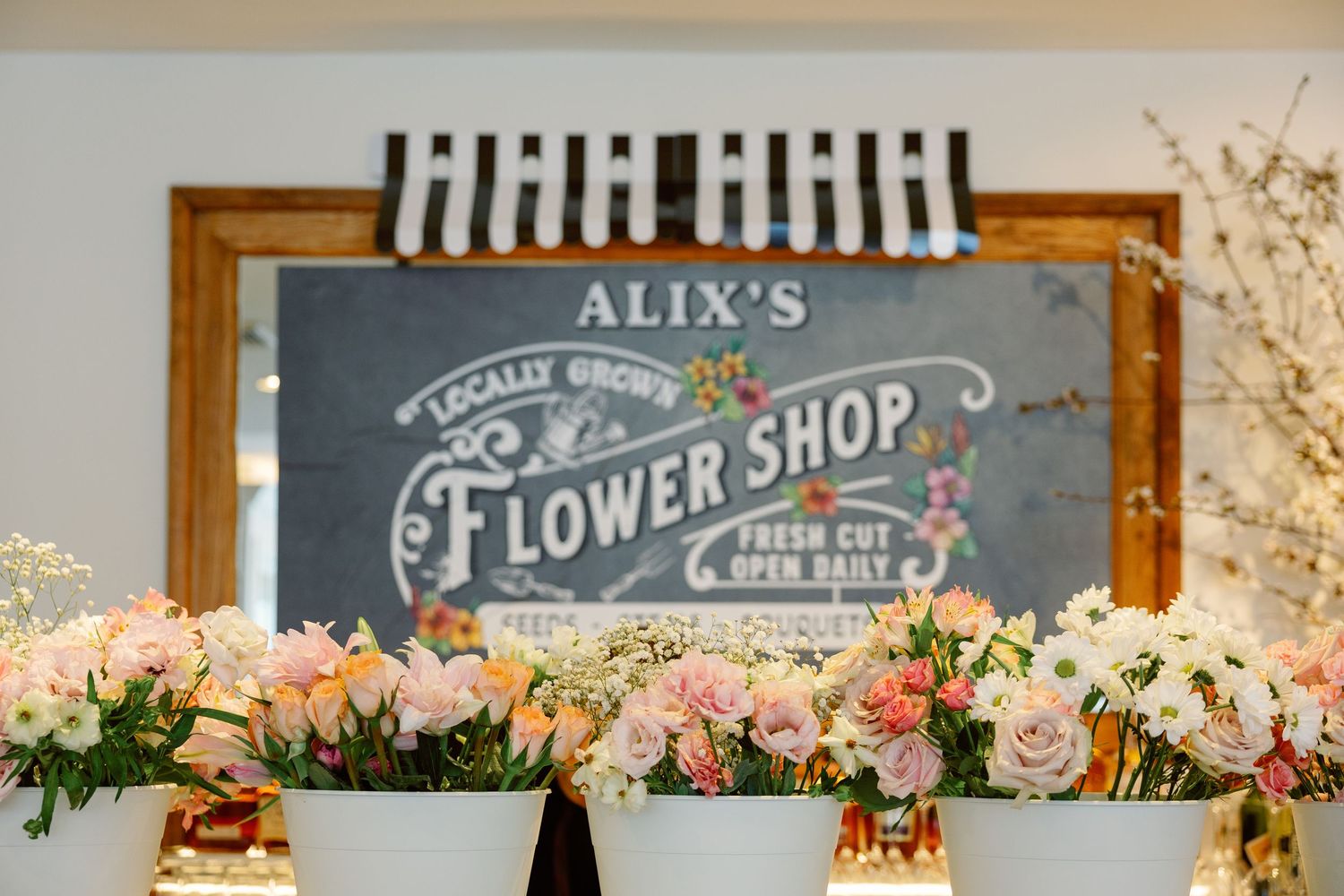 Colorful floral arrangements displayed beneath Alix's Flower Shop chalkboard sign with pink roses.