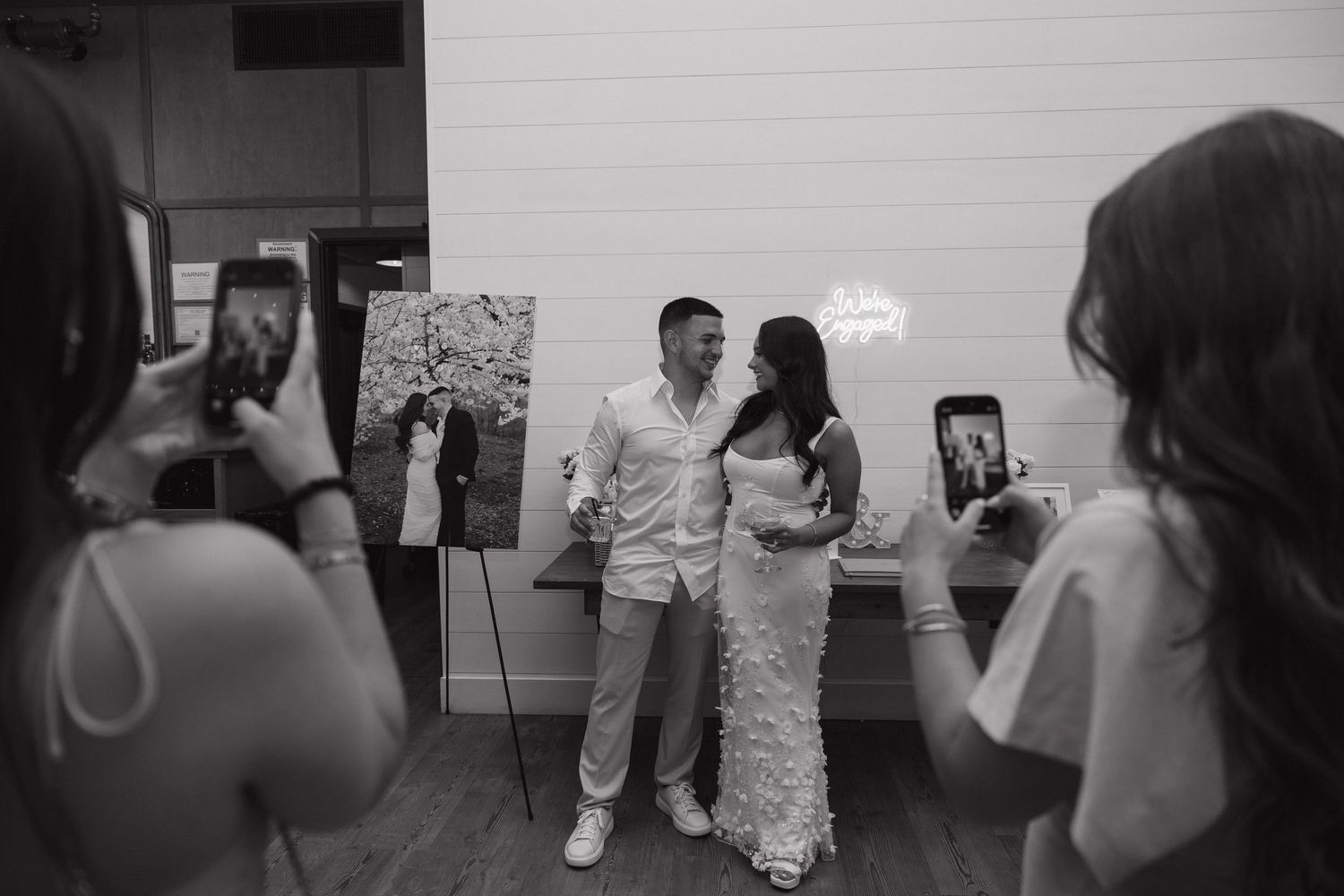 Black and white photo of a couple posing for photos at their wedding reception event.