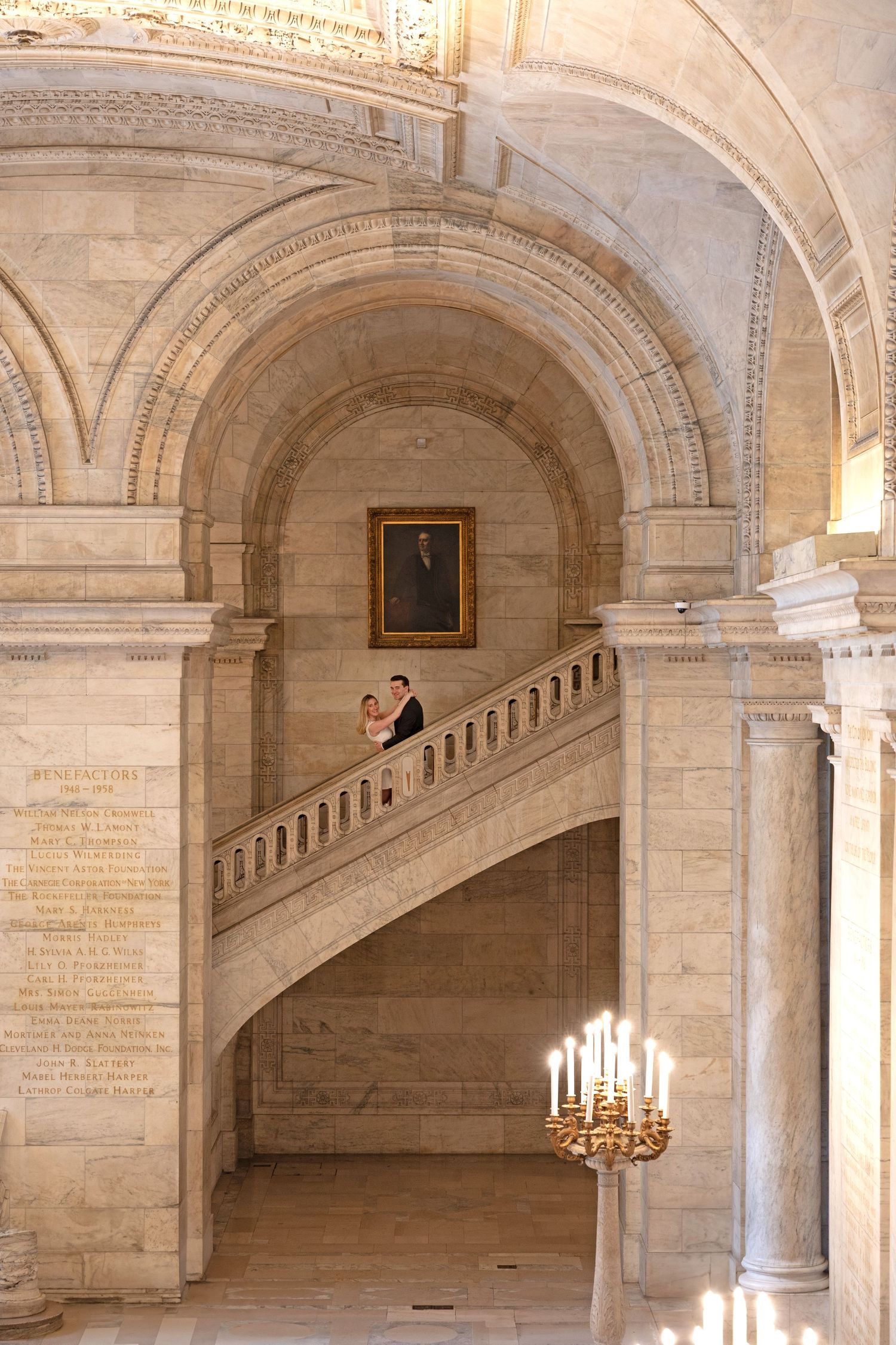Wedding couple posing on elegant marble staircase inside a grand historic building.