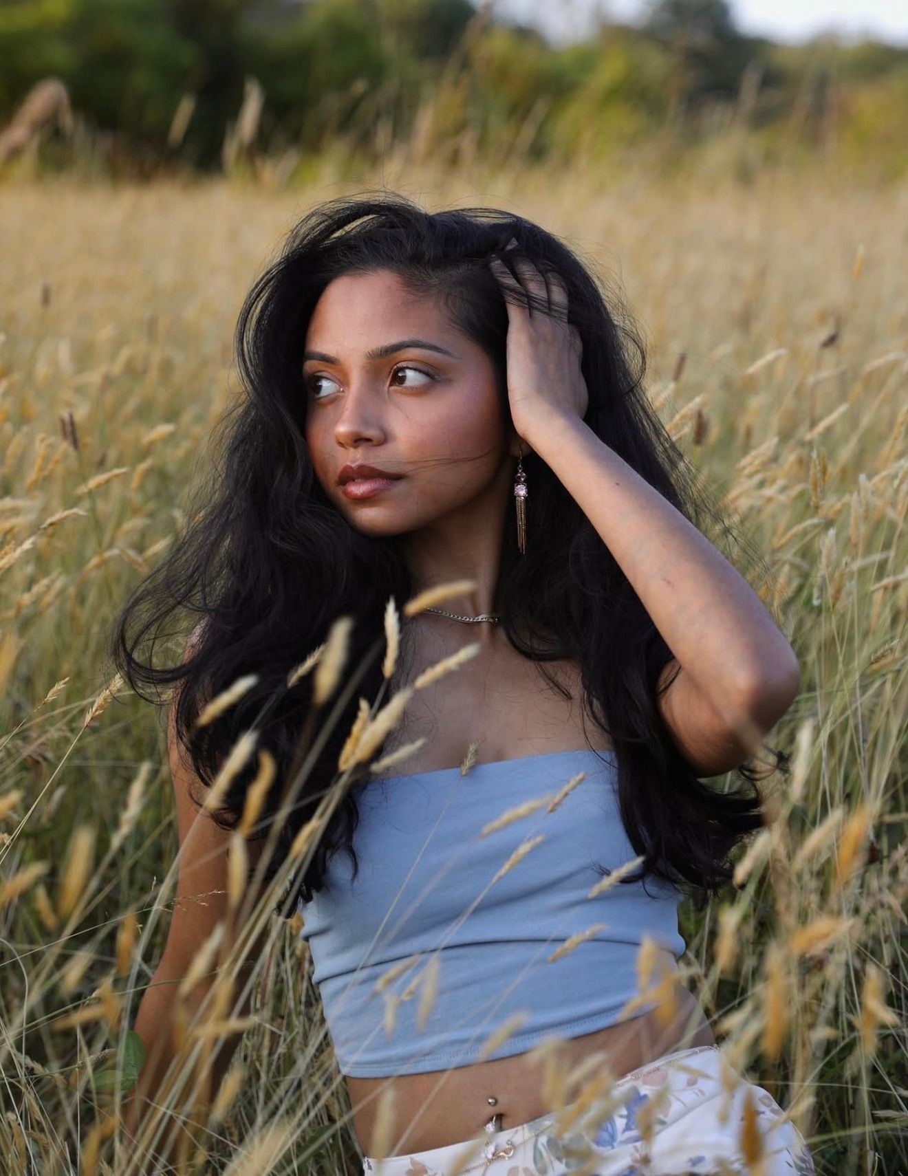 Artistic portrait in a wheat field with soft golden light and flowing hair.