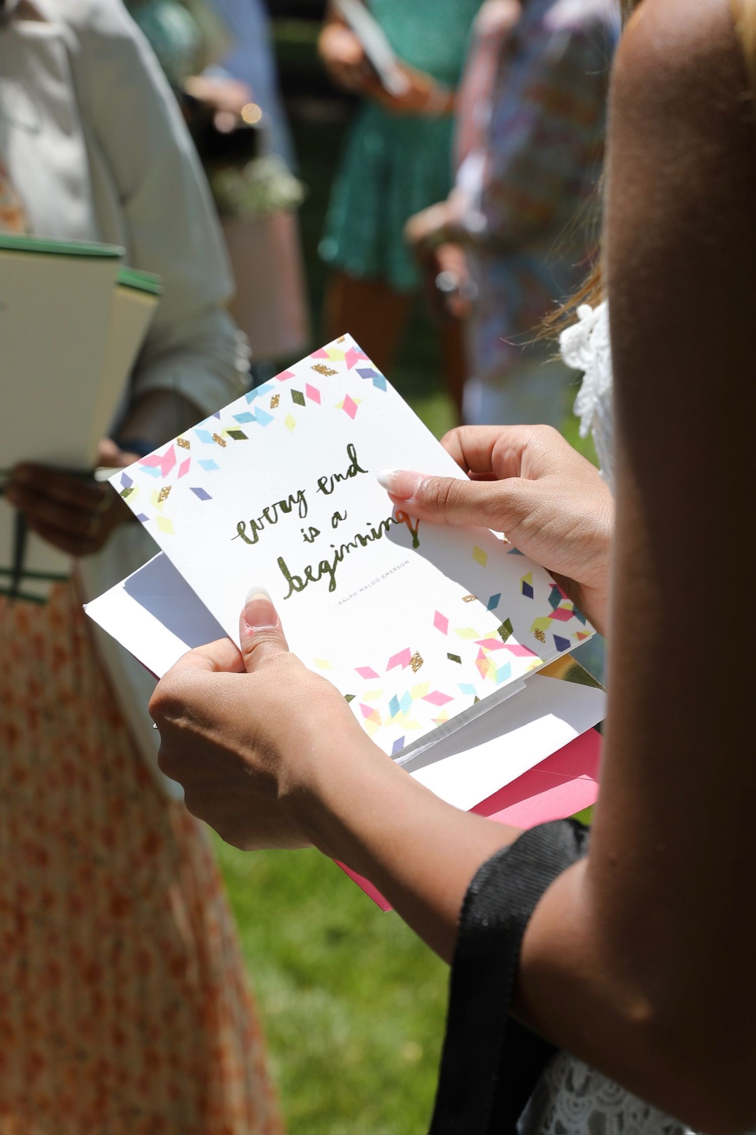 Someone holding and reading a handwritten greeting card with floral decorations on it.