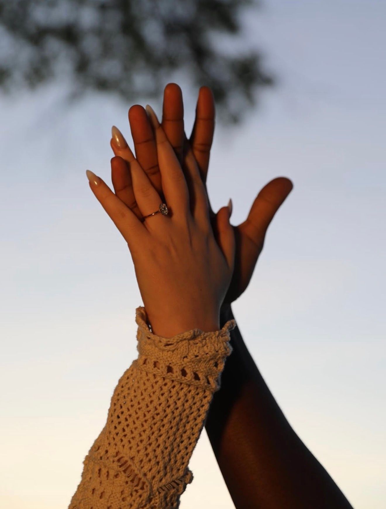 Hands silhouetted against sky wearing crocheted wrist warmers.