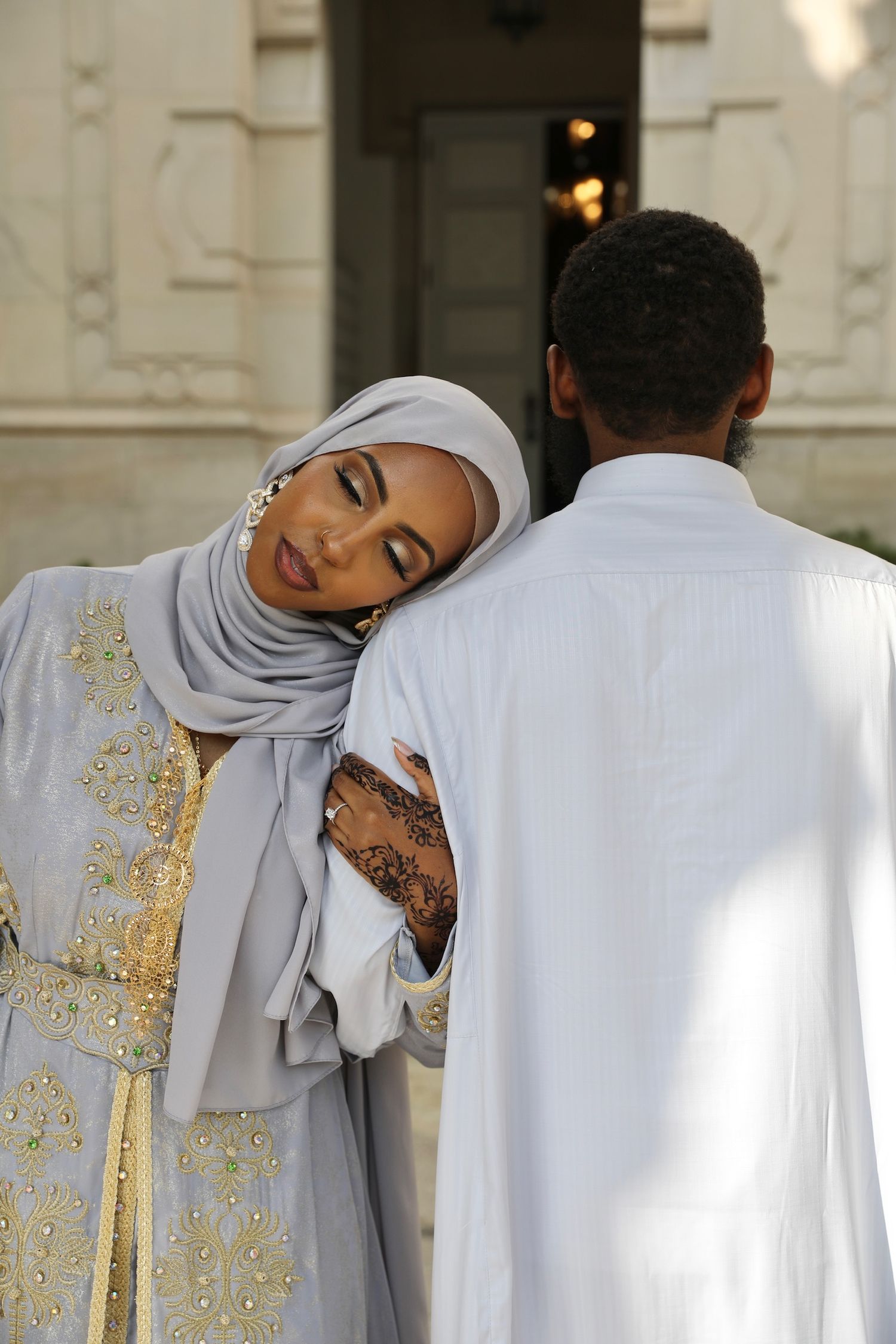 A couple in traditional white and gold attire embrace during what appears to be a wedding ceremony.