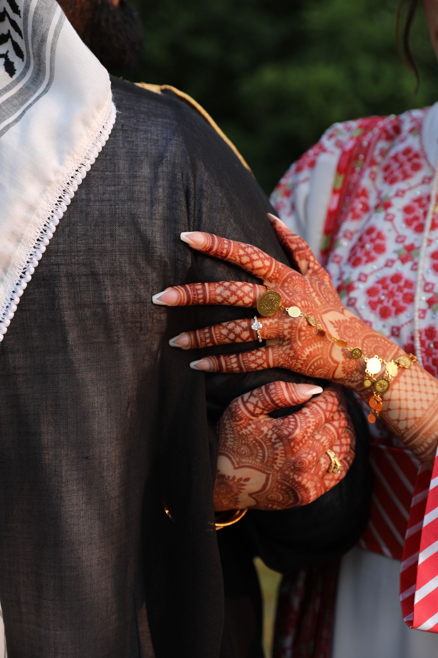 Close-up sequence of hands adorned with traditional henna designs and gold jewelry against black and red clothing.