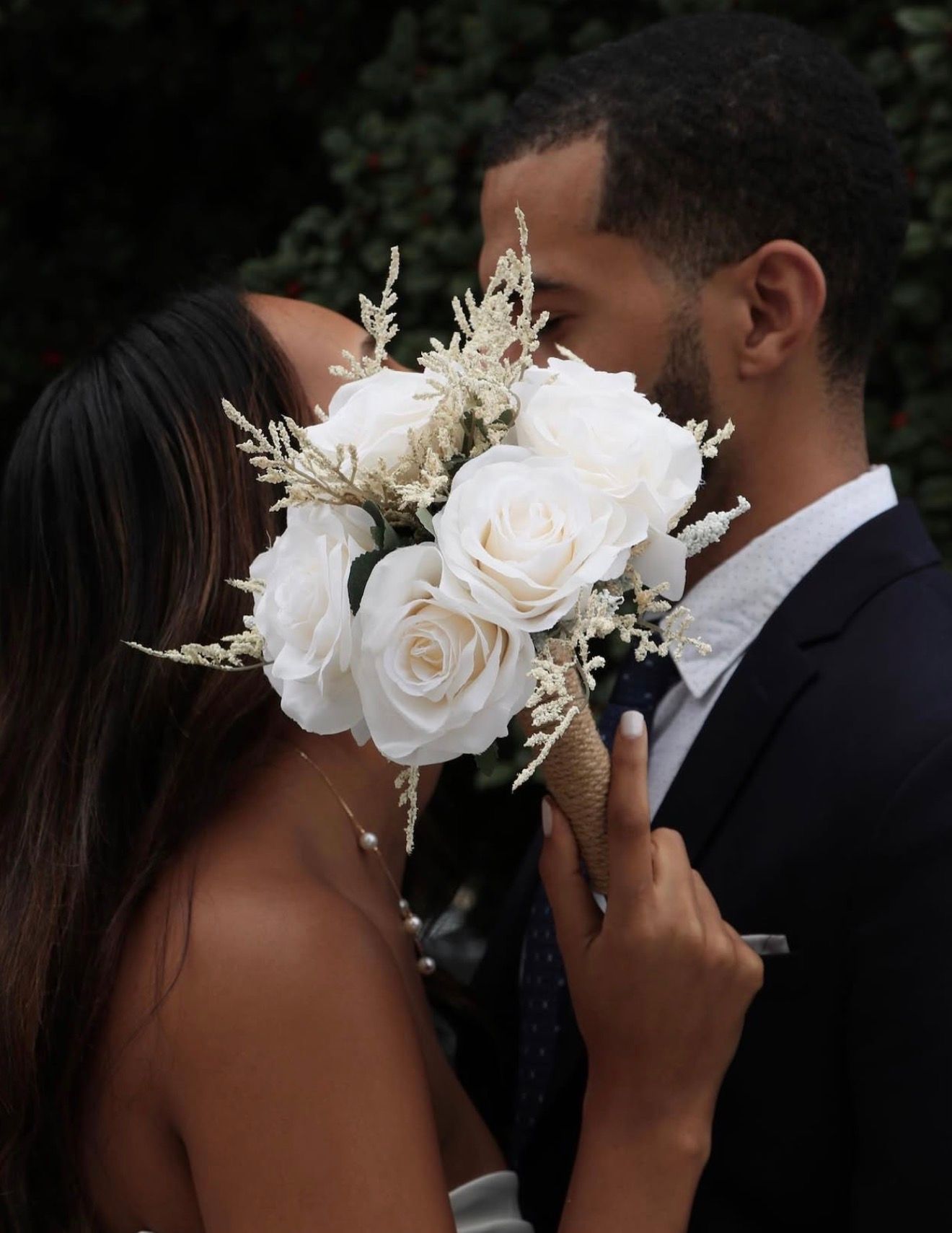 Romantic couple holding white roses during intimate wedding moment.