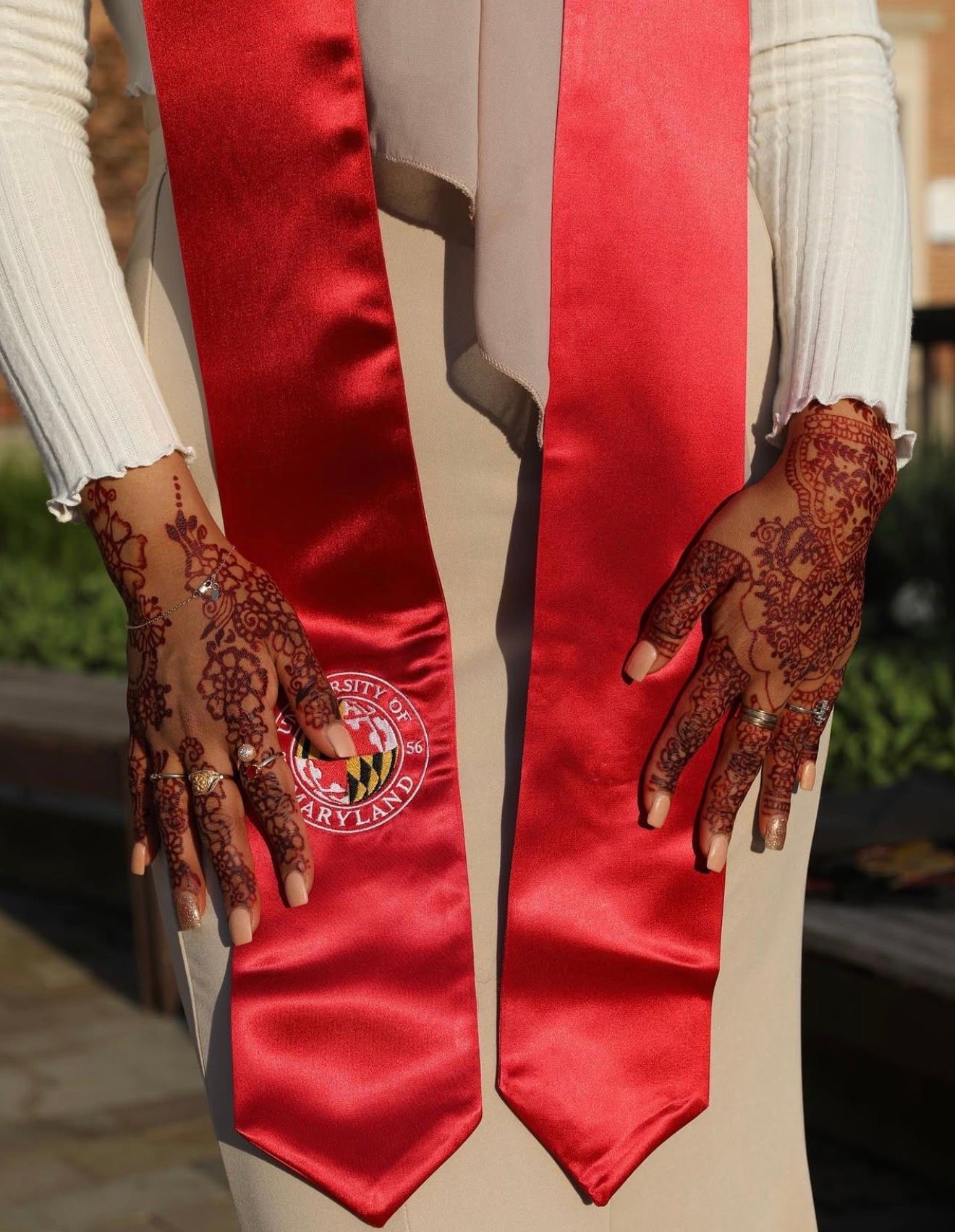 Intricate henna designs adorning hands against red satin fabric.