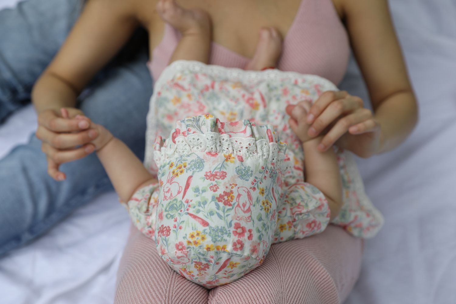 Close-up view of hands holding and folding colorful floral patterned fabric against a light background.