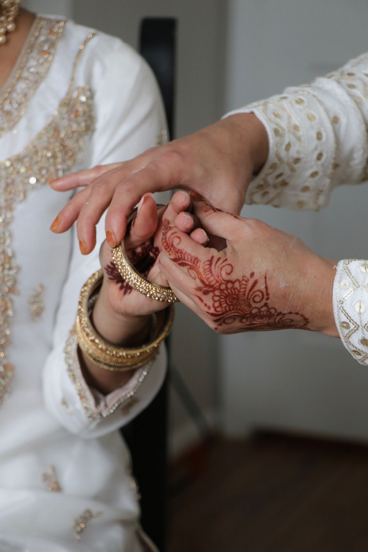 Close-up sequence of hands showing intricate henna designs during a traditional wedding ceremony.