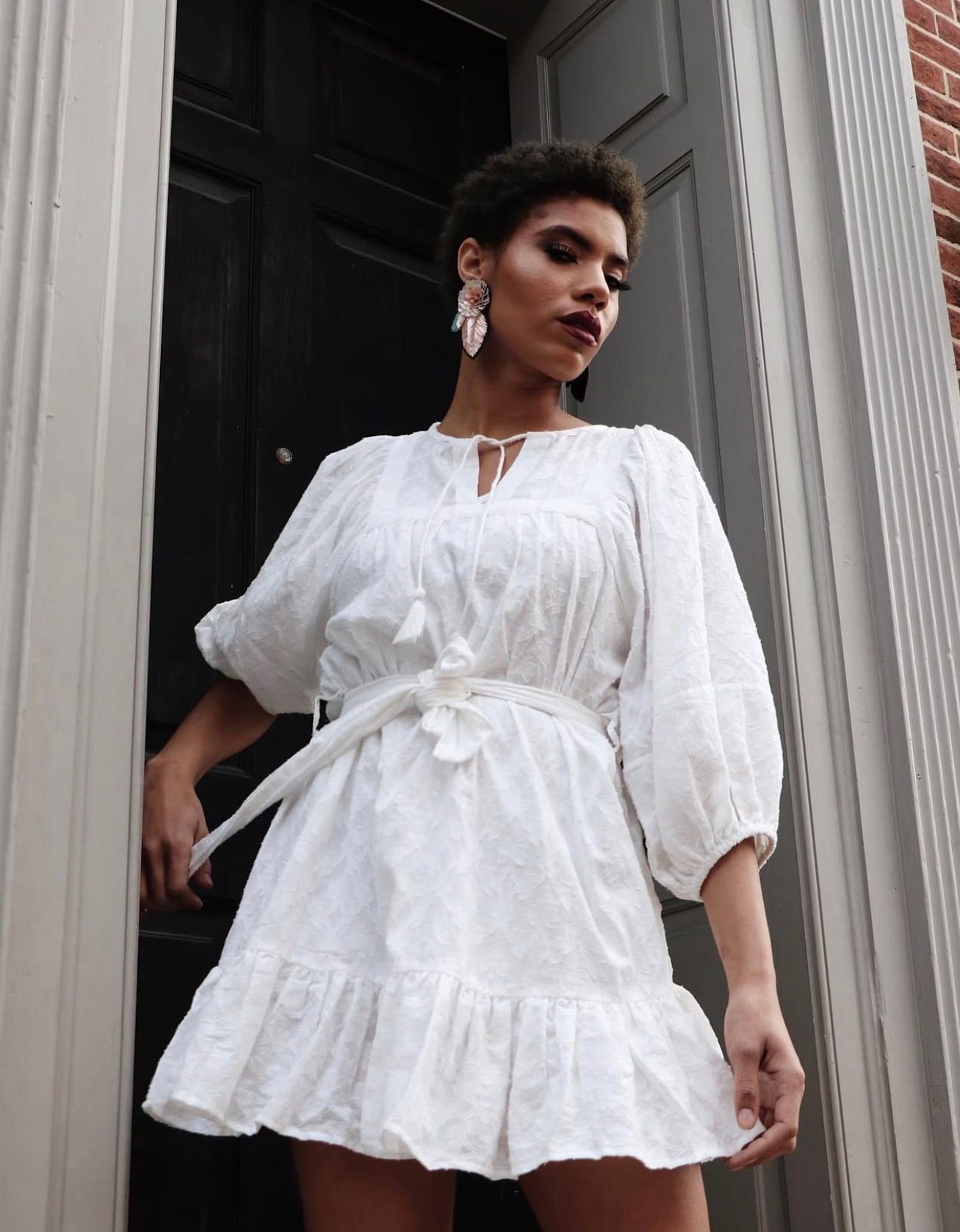 Fashion portrait featuring white ruffled dress against classical columns.