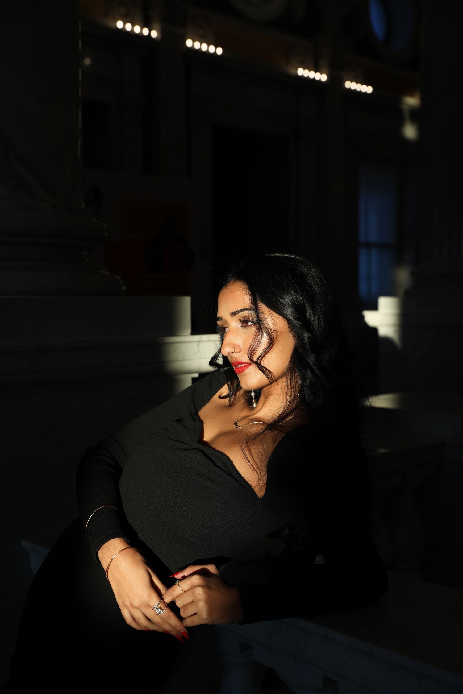 Dramatic portrait in dark setting with moody lighting and shadows highlighting a black outfit against a dark background.