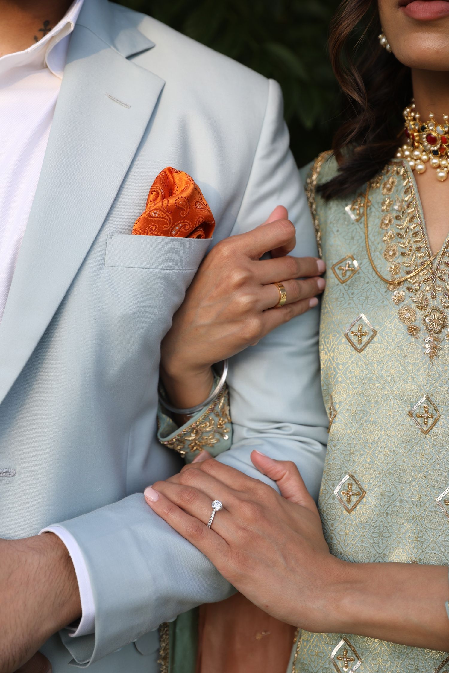 Close-up of couple in formal wear showing romantic embrace with light blue suit jacket and beaded dress details.