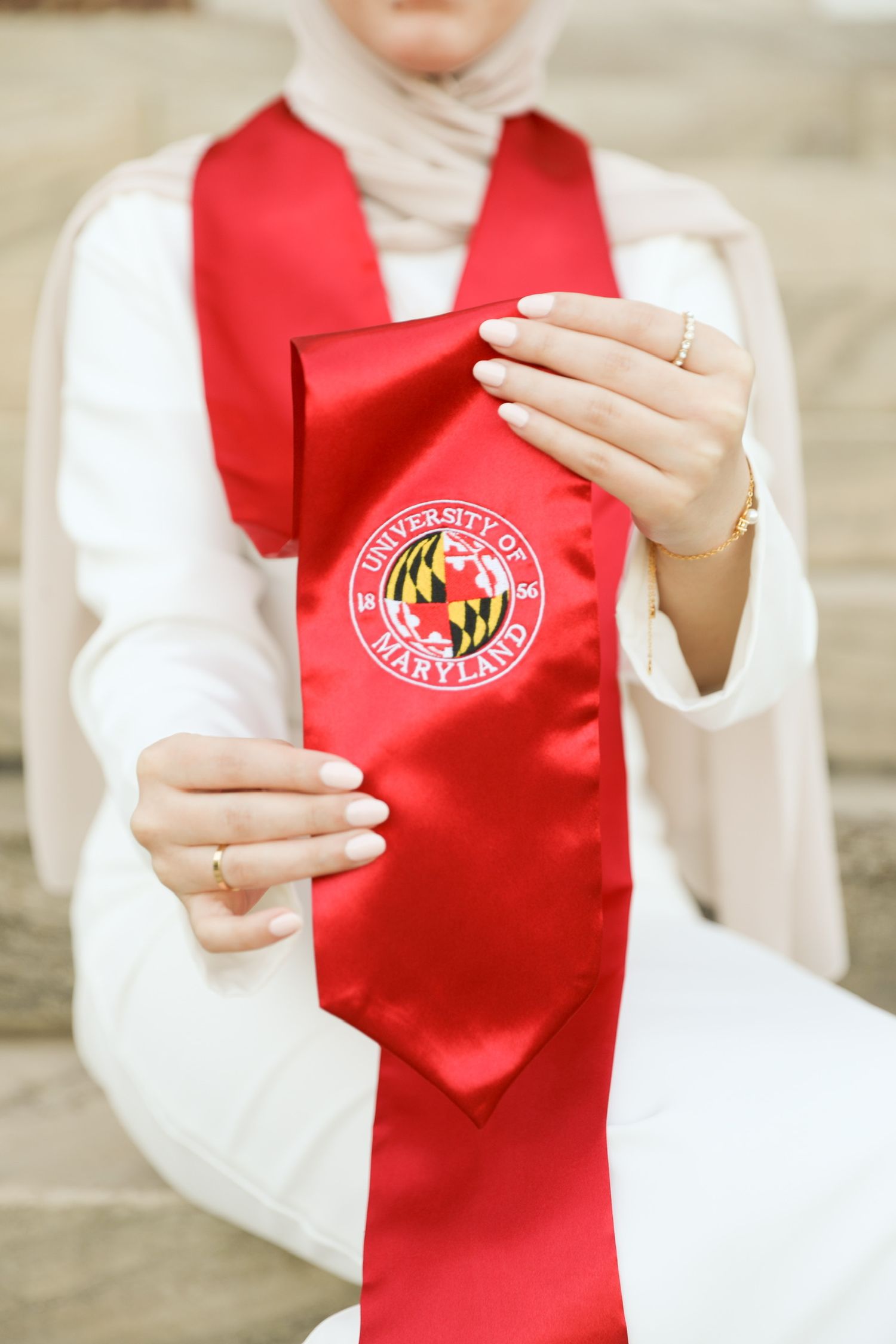 Close-up view of hands wearing white sleeves and a red vest with a university logo emblem.