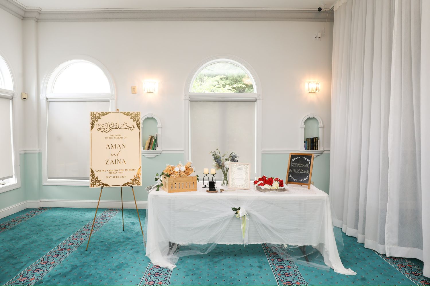 White fabric curtains and walls create an elegant backdrop in a spacious event venue with decorative lighting fixtures.