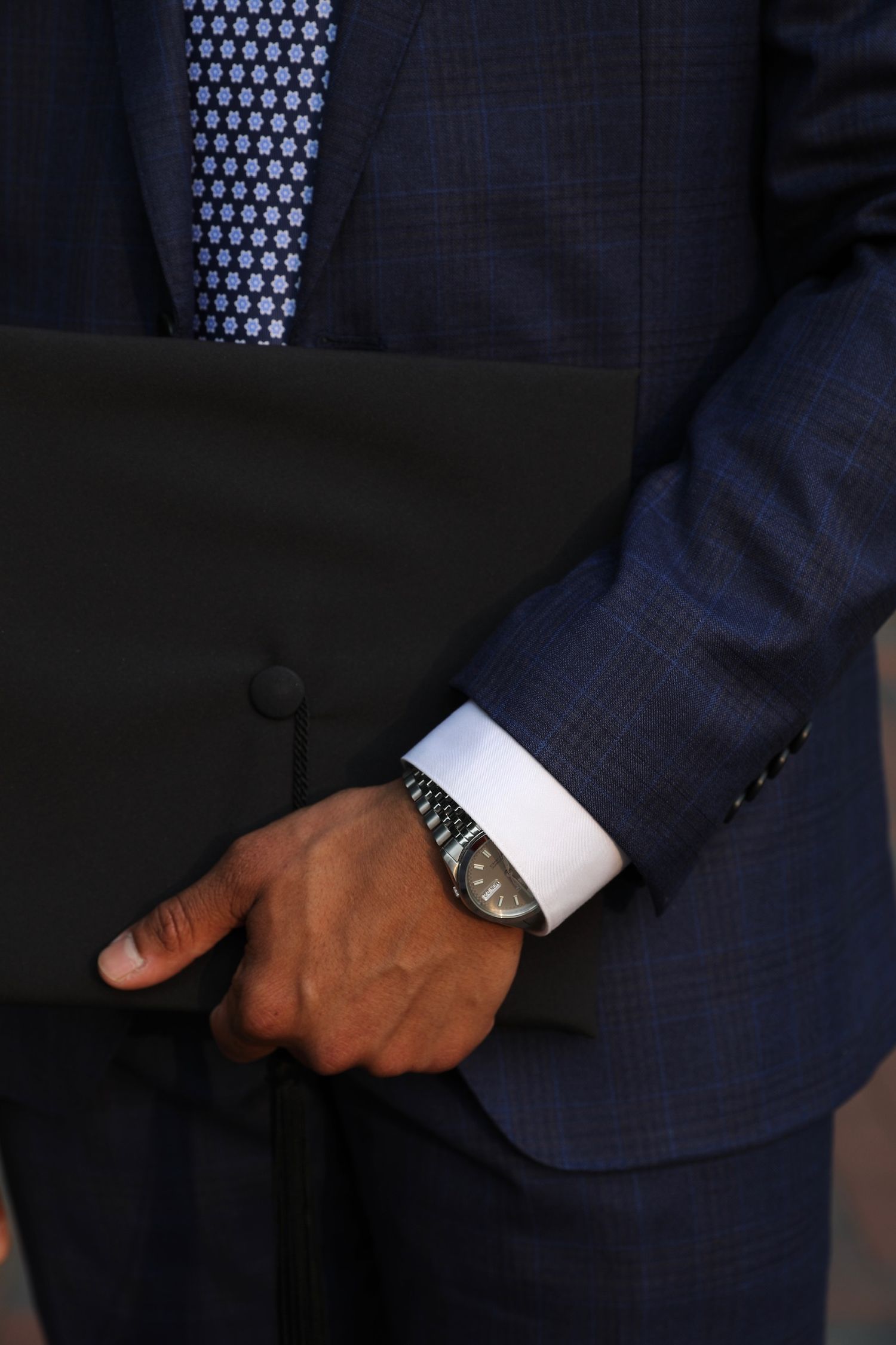 Close-up view of a navy blue suit sleeve with white shirt cuff and elegant wristwatch detail.
