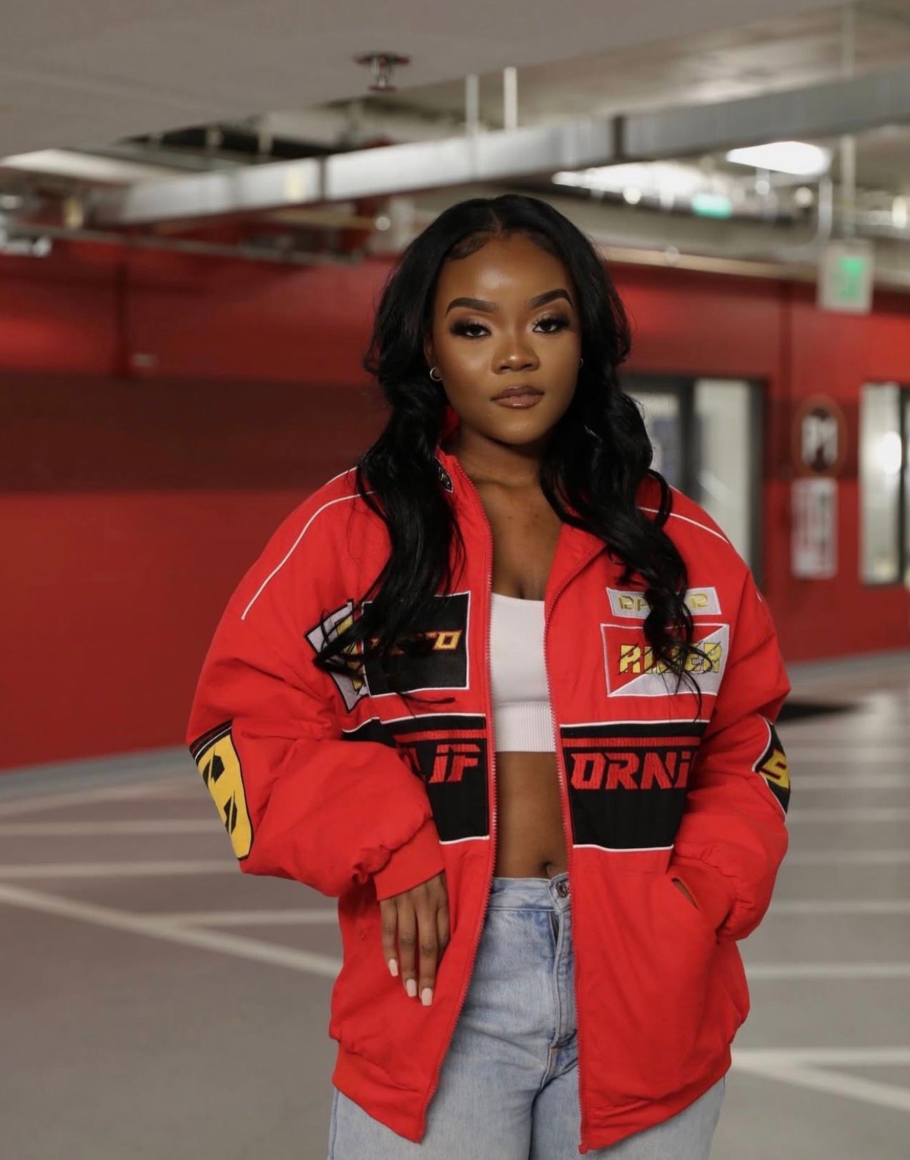 A fashion photoshoot sequence showing a model in a red bomber jacket and jeans posing in a parking garage.