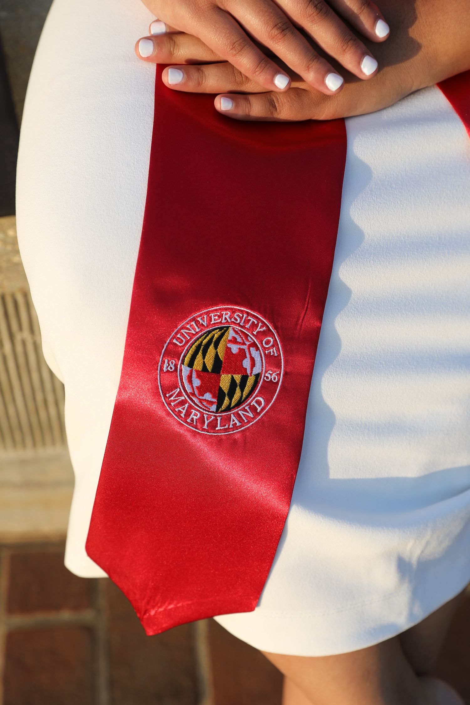 Red graduation stoles with university logos displayed in a row against a white background.