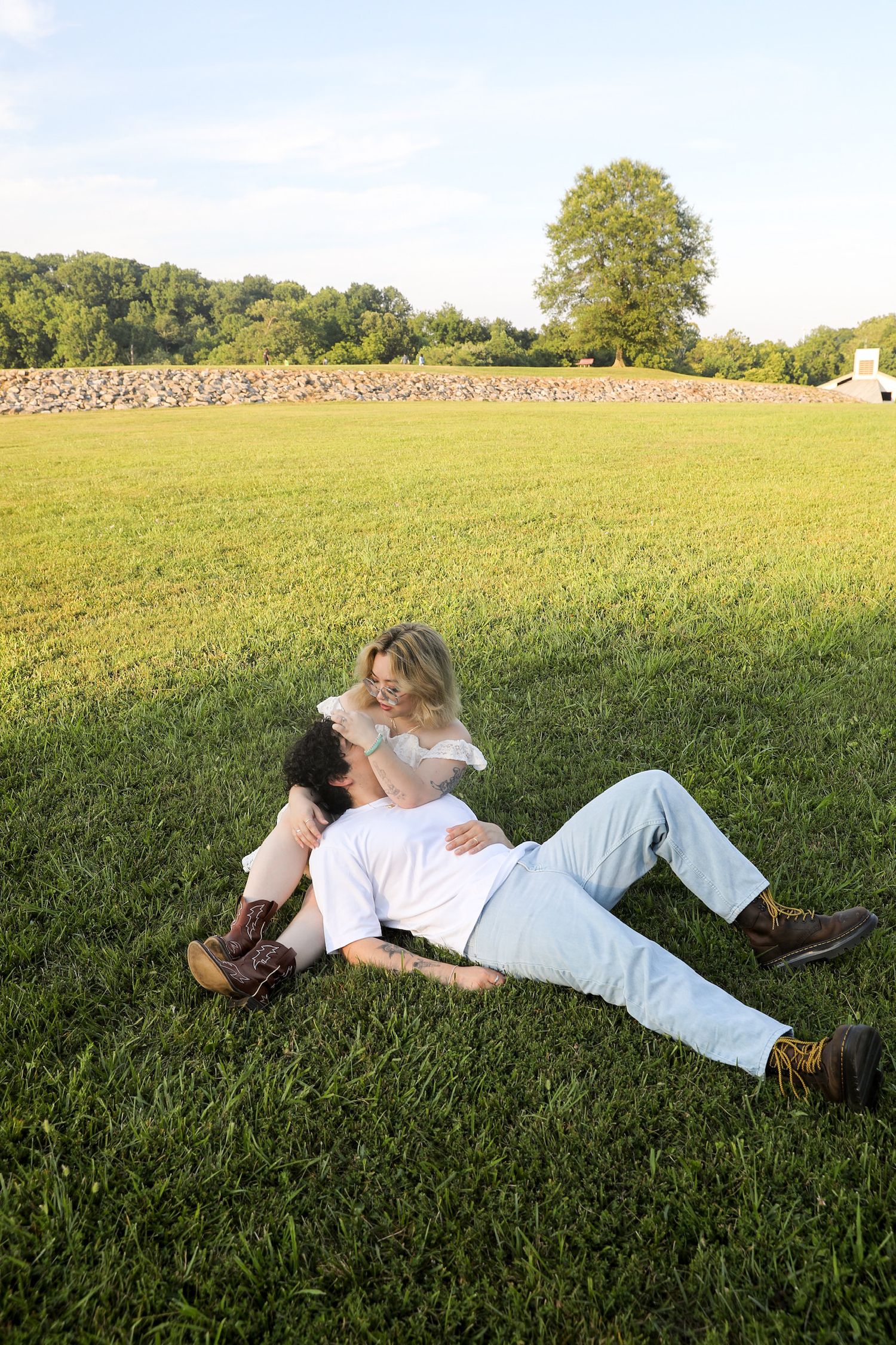 Two people relax and lay down together in a peaceful green field on a sunny summer afternoon.