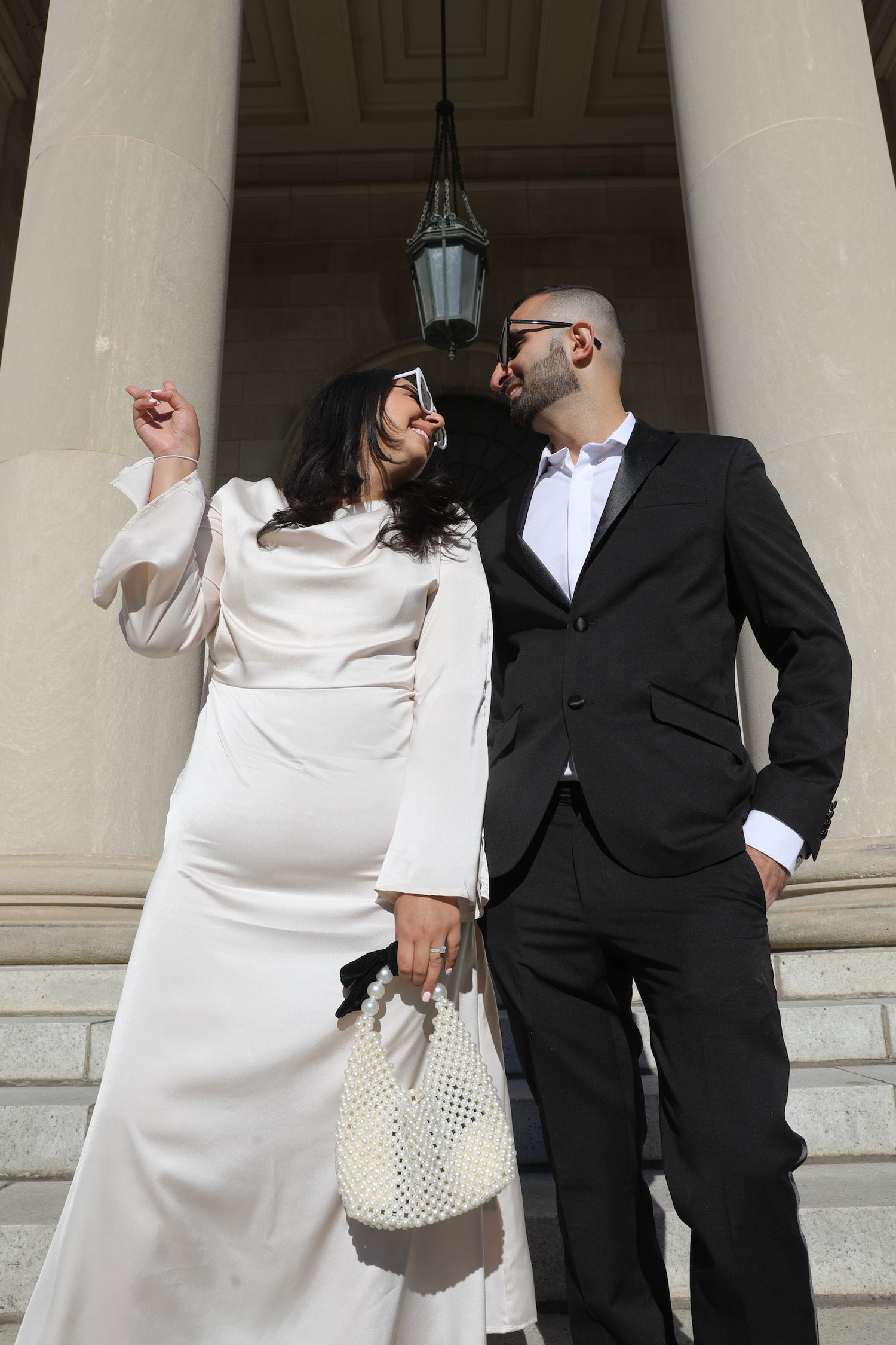 A couple in white dress and black suit poses playfully in a sequence of photos on stone steps.
