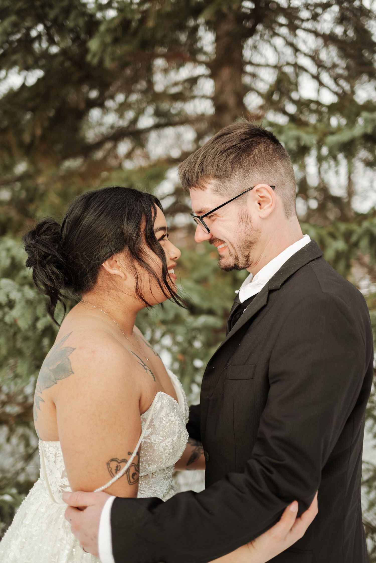 Intimate winter wedding portraits captured among evergreen trees.