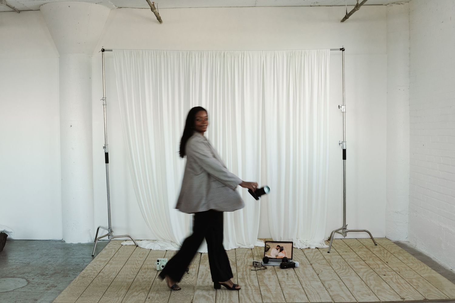 Creative professional walking through minimalist studio space with photography equipment.