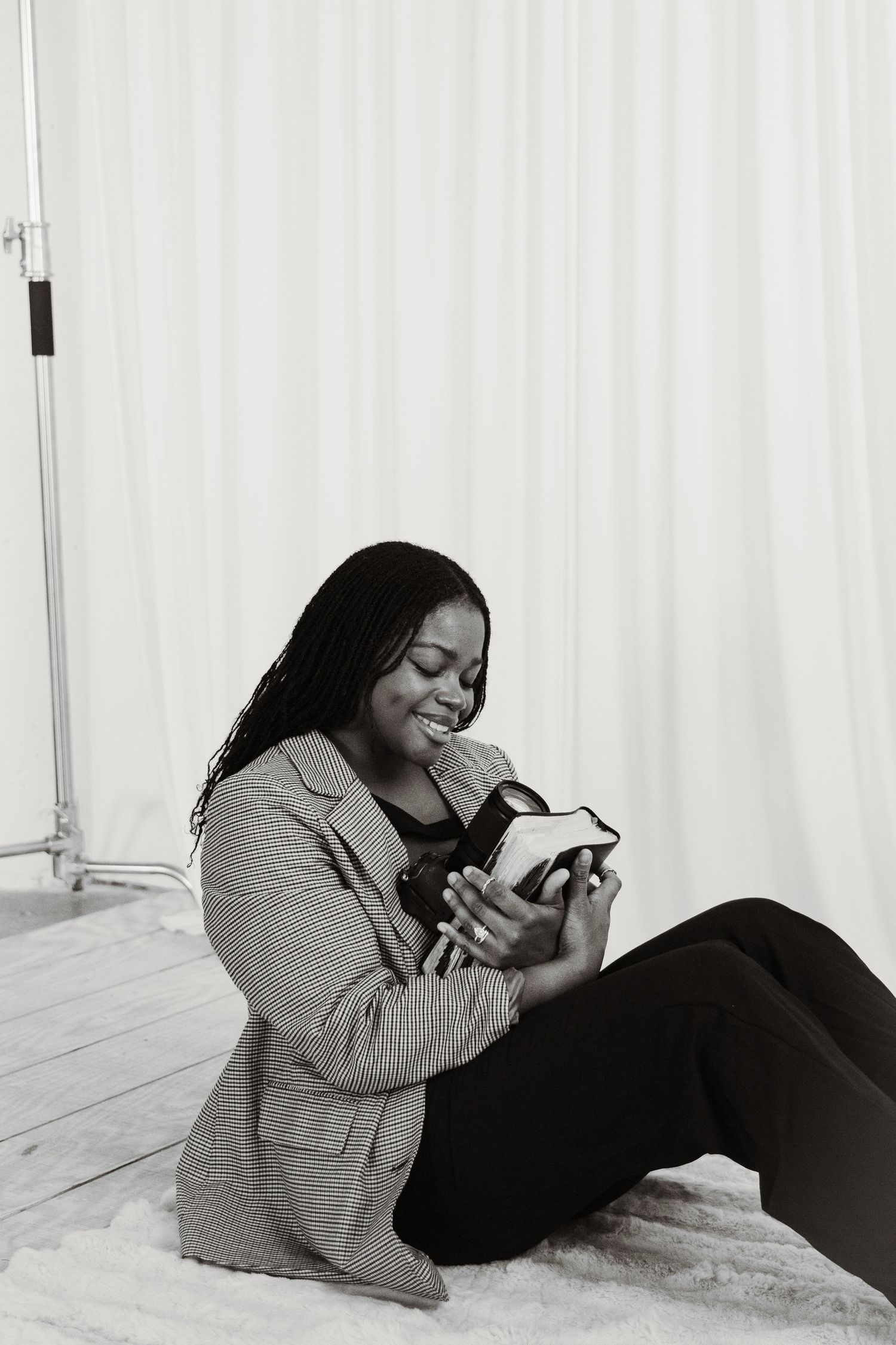 Photographer relaxes on floor while reviewing photos on camera in bright studio setting.