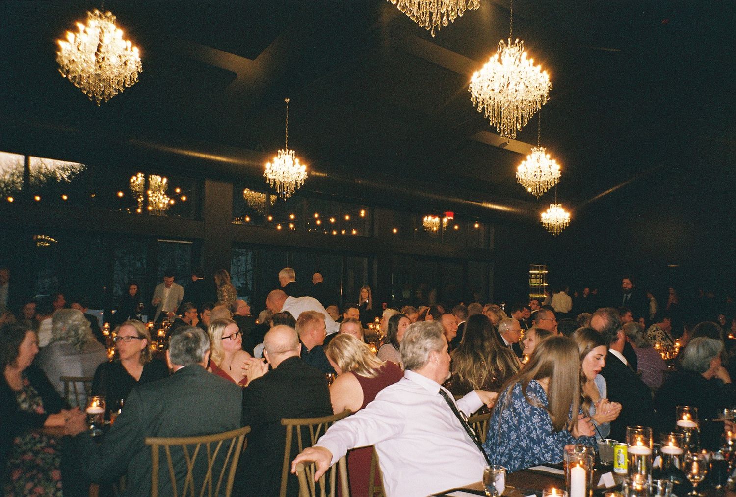 Elegant banquet hall filled with guests dining under crystal chandeliers at a formal event.