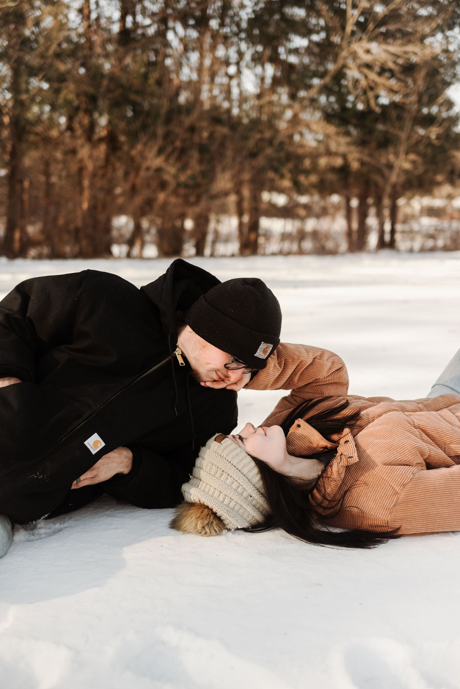 couples laying down in the snow in Minnesota